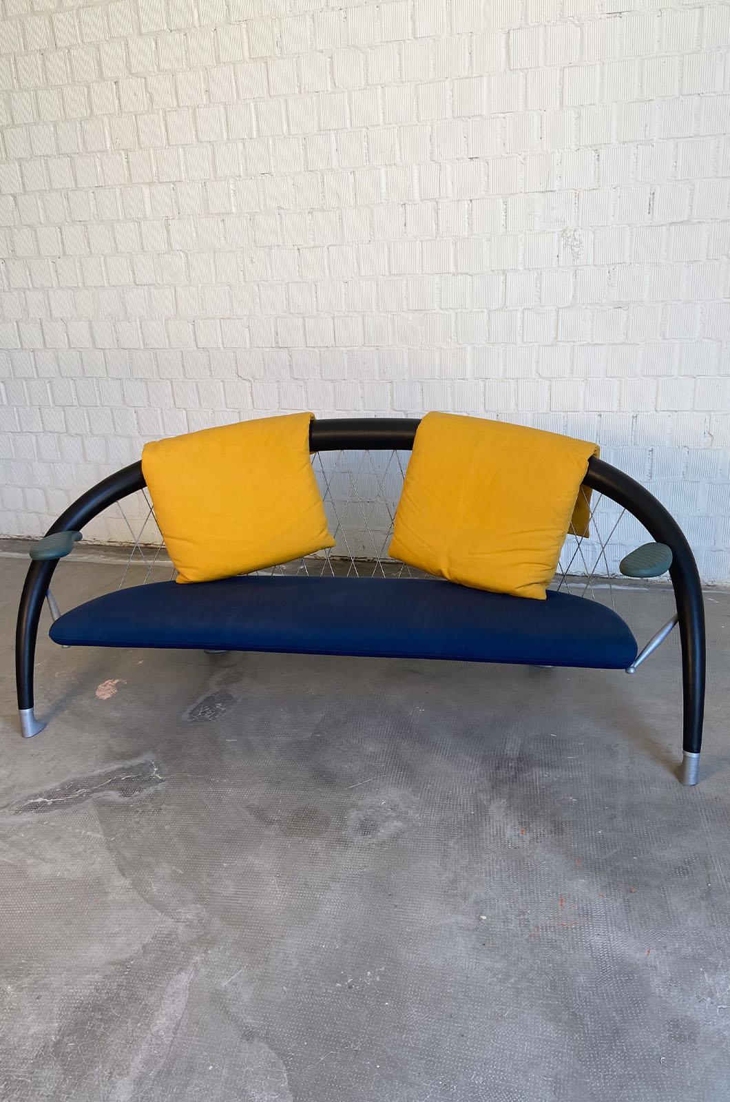 Le canapé Axale a été conçu par Andrea Branzi et produit par Cassina en 1990. Le canapé est doté d'un cadre en maille d'aluminium et de sections tubulaires recouvertes de cuir noir. Les accoudoirs sont en plastique bleu et l'assise rembourrée est