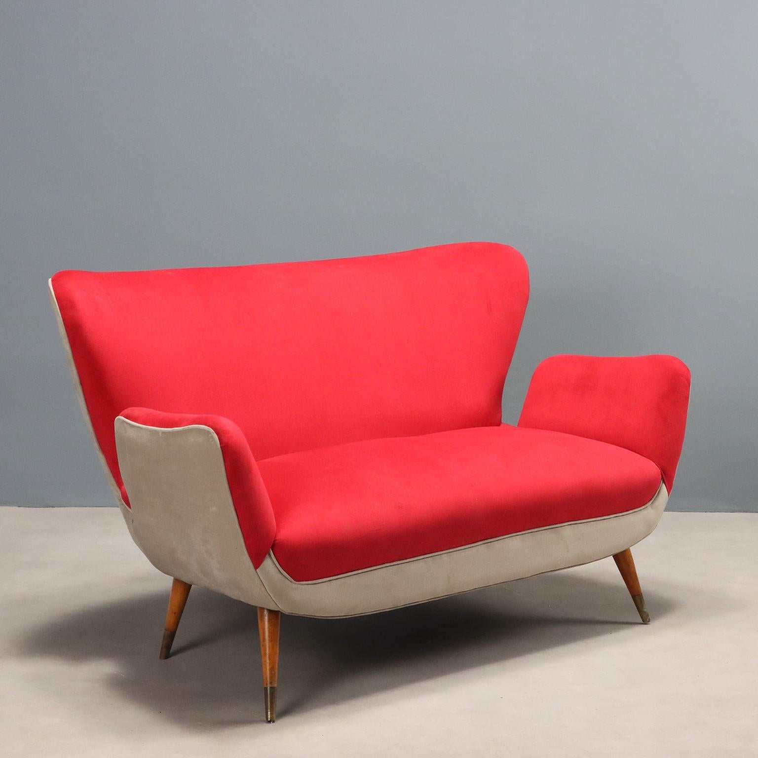 Vintage two-seater sofa with back and armrests with curvy lines, upholstered with foam and covered in two-tone red and gray fabric. Seat that can be renewed in upholstery by choosing from the various proposals in our warehouses.