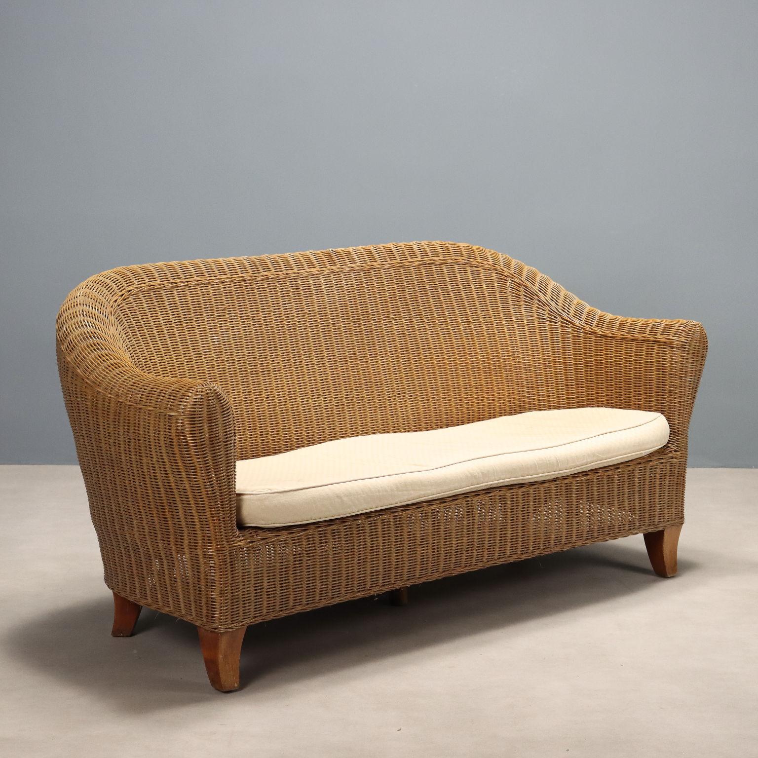 Divano vintage realizzato in vimini con cuscino bianco. In buone condizioni generali con qualche segno del tempo.