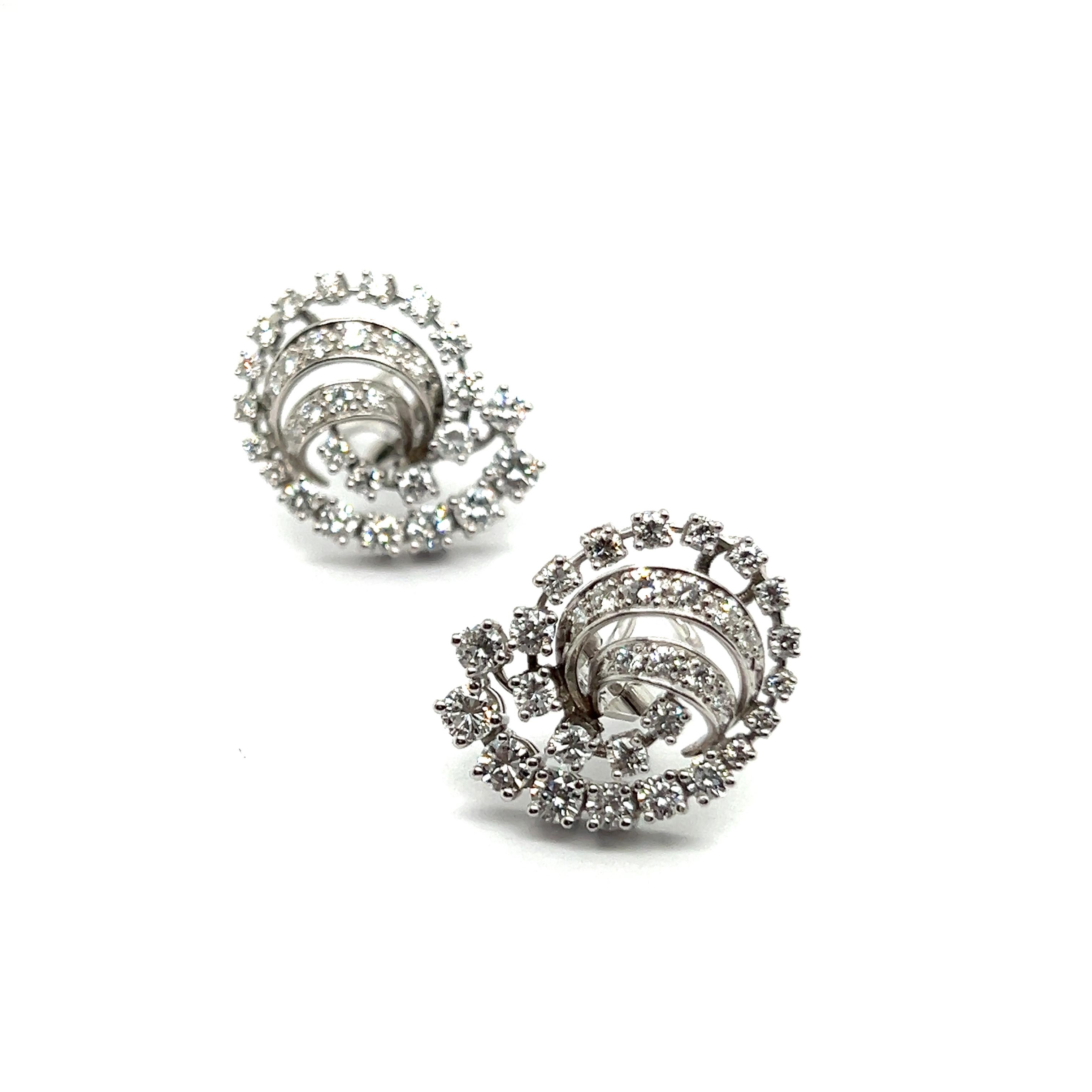 Adorn yourself with celestial elegance in these divine earrings. Crafted in 18 Karat white gold, they boast a mesmerizing swirl of 64 brilliant-cut diamonds, totaling 2.00 carat. Each stone of G-H color and vs clarity sparkles like the brightest