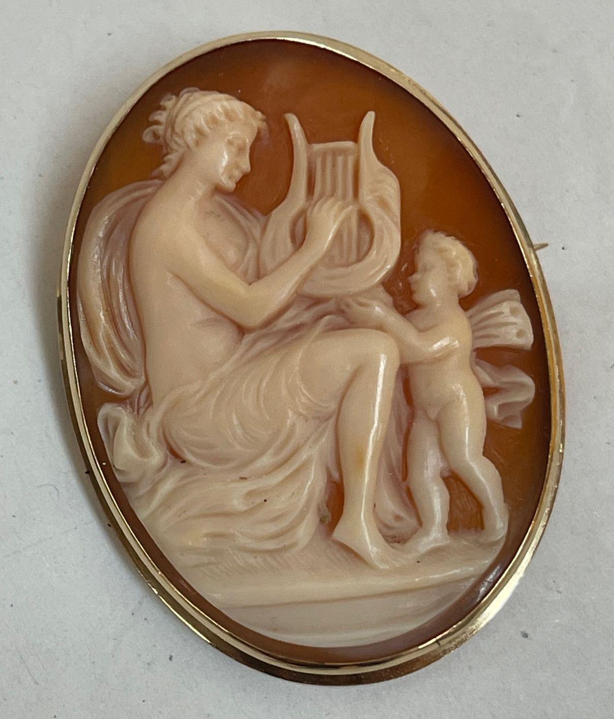 Beautiful Carved Shell Cameo Pin/Pendant. Hand carved scene depicting Aphrodite playing a Lyre with a winged Cherub by her side. DIVINE MUSICAL HARMONY. Hand set in 14K Yellow Gold frame. Rendered with remarkable detail and warmth, so unusual to