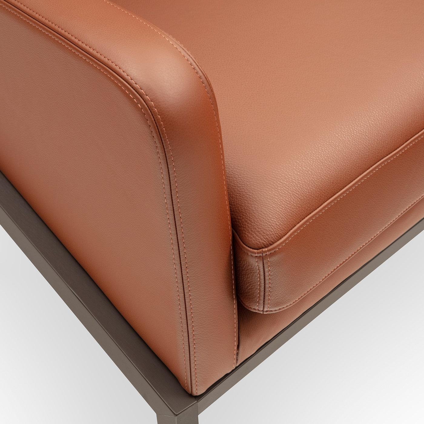 Defined by sculpted volumes tracing a dynamic silhouette, this sophisticated armchair covered in prized brown leather will be ideally displayed in studies or homes with a neutral color palette. The generously padded silhouette ensures great comfort,