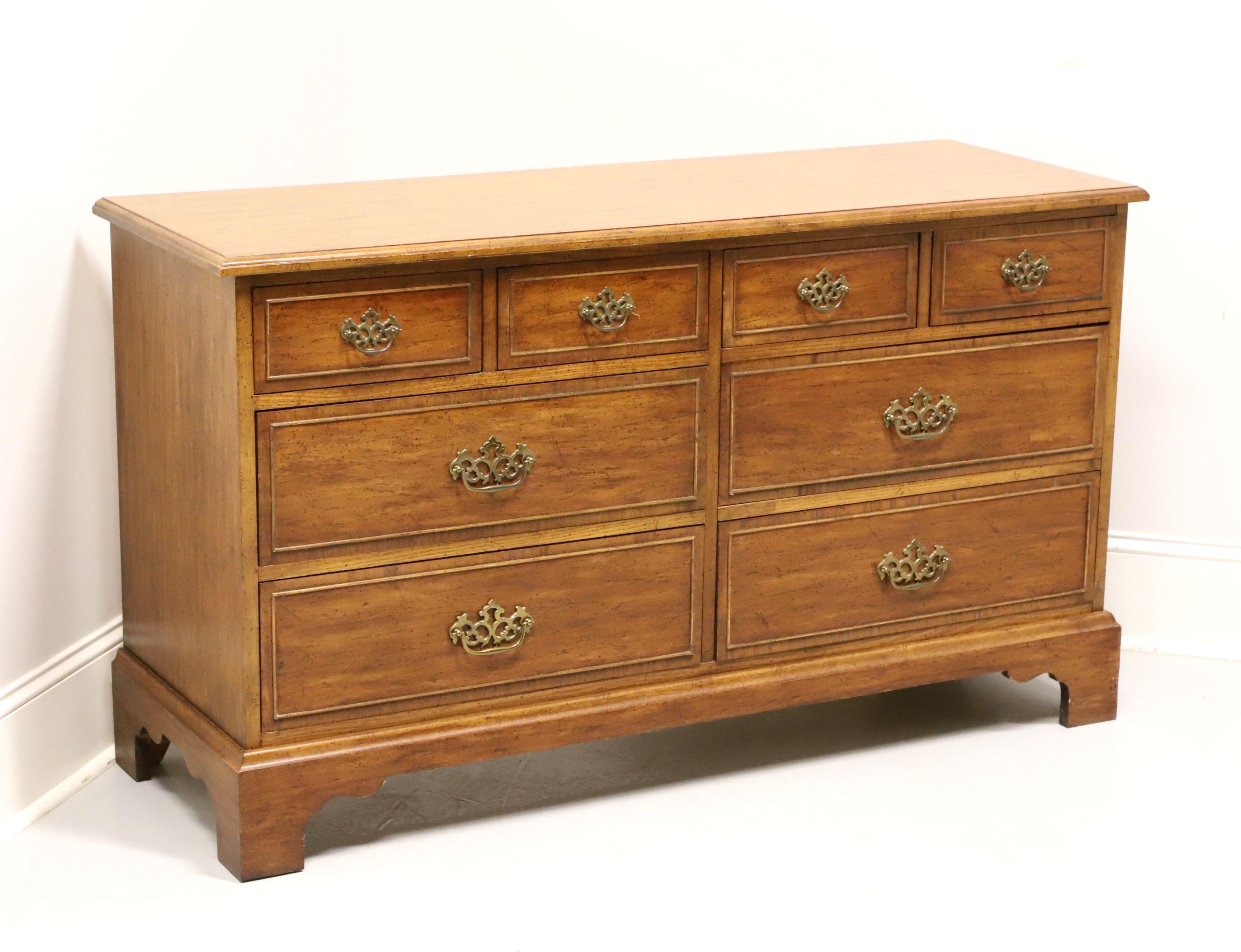 A Chippendale style double dresser by Dixie Furniture, from their Sheffield Manor Collection. Pecan with a distressed finish, brass hardware, cockbeading to drawer fronts and bracket feet. Features four smaller over four larger drawers of dovetail
