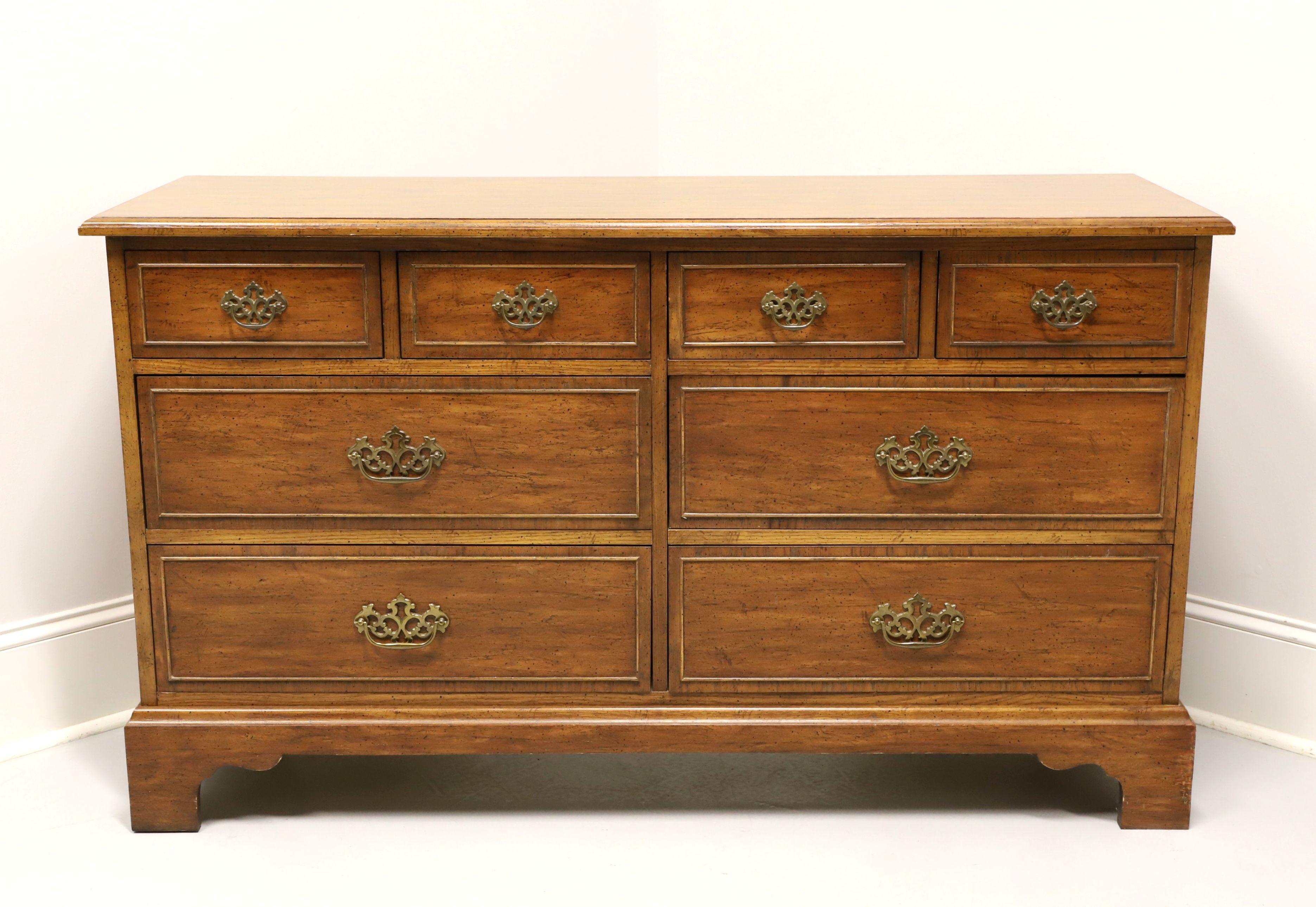 A Chippendale style double dresser by Dixie Furniture, from their Sheffield Manor Collection. Pecan with a distressed finish, brass hardware, bevel edge to the top, cockbeading to drawer fronts, and bracket feet. Features four smaller over four