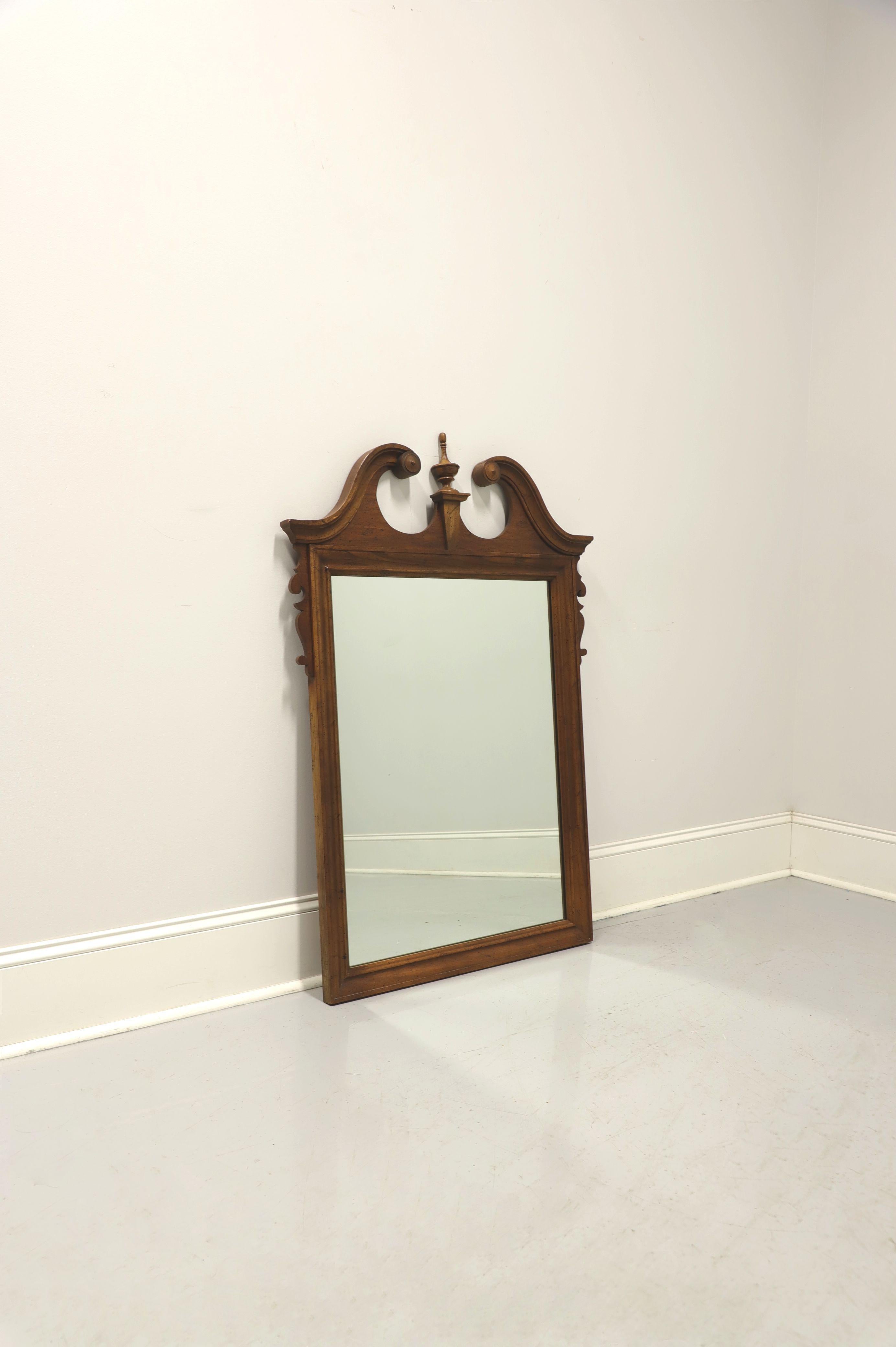 A Chippendale style wall or dresser mirror by Dixie Furniture, from their Sheffield Manor Collection. Mirrored glass in a distressed pecan frame with pediment and center finial to top. Made in Lenoir, North Carolina, USA, in the late 20th