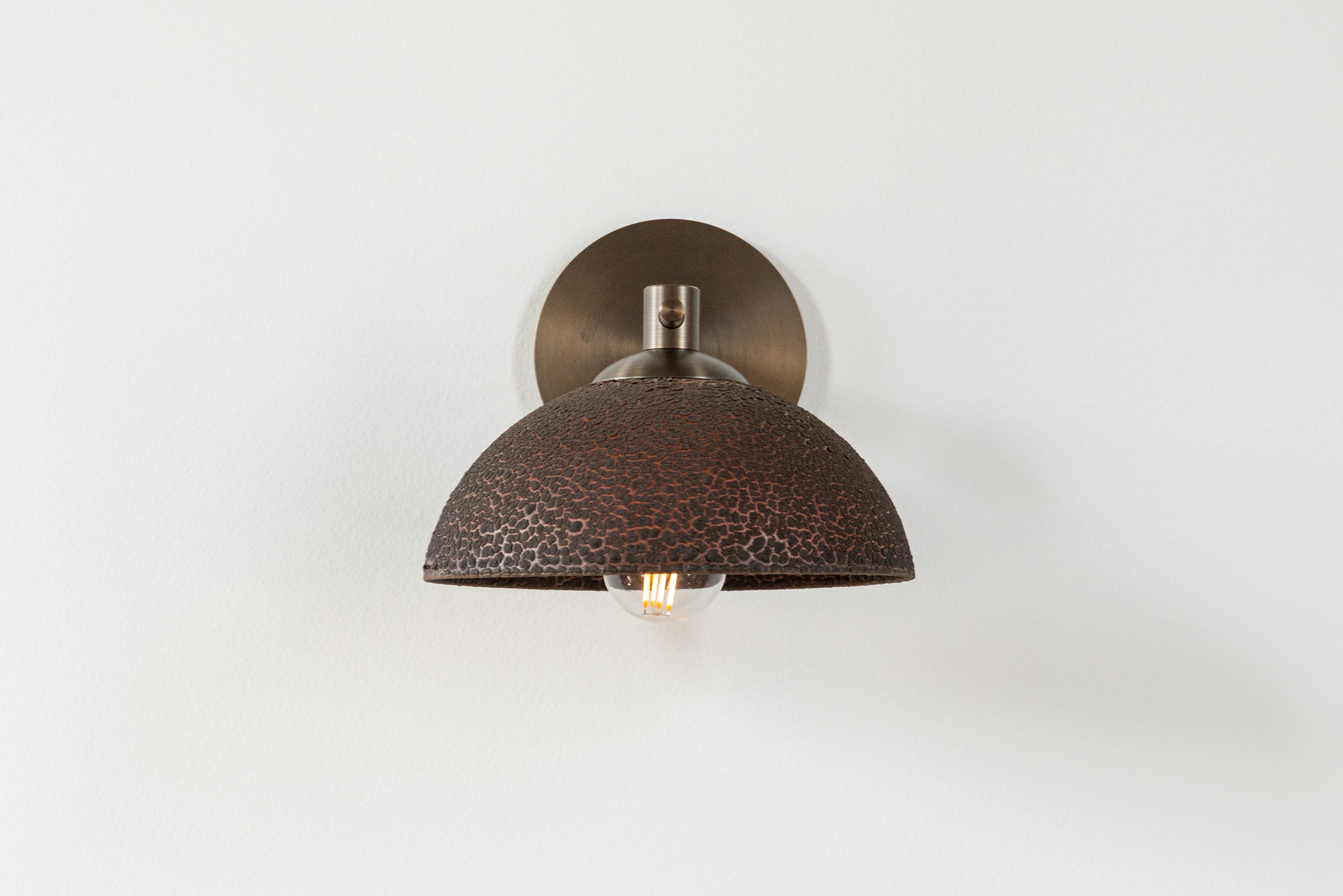 With a modern form and refined finishes, the stepping effect of the Dixon Sconce’s tubing mimics nature’s growth on flower stems. The reflector is hand-cast from terracotta and glazed with either a matte or textured lichen glaze, which you choose.