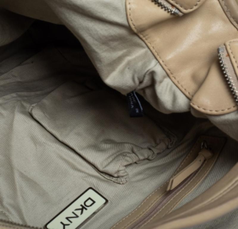 This Dkny hobo will surely assist you on all days. It has been designed in a beige pleated leather body and is held by a single handle. This bag has a zip fastening, a fabric-lined interior, and silver-tone hardware.