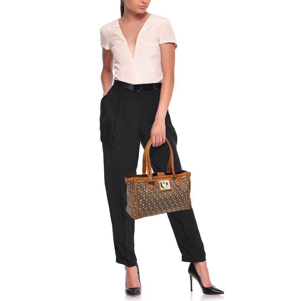 Conçu pour la femme moderne, le fourre-tout DKNY est idéal pour la citadine qui fait la navette tous les jours, aime faire du shopping et voyage souvent. Réalisée en toile, cette création est rehaussée d'accessoires dorés et d'une double poignée.