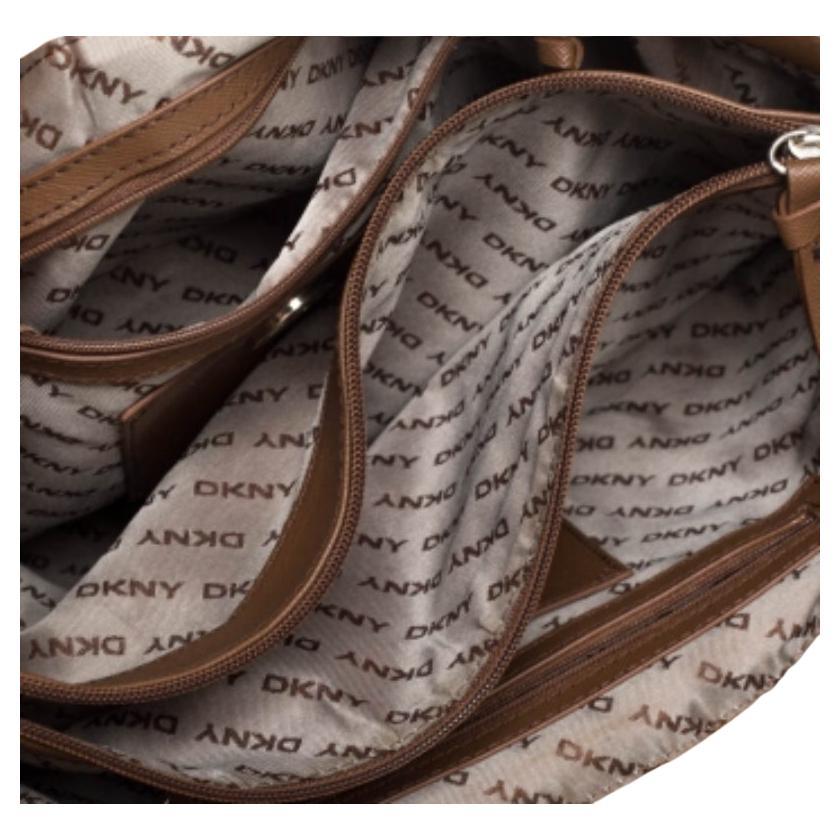 Este bolso tote de Dkny, confeccionado en lona estampada y piel, tiene el tamaño perfecto. Su exterior en tonos beige y tostado se combina con un bolsillo con solapa en la parte delantera, bolsillos abiertos en los laterales y asas dobles. Forrado