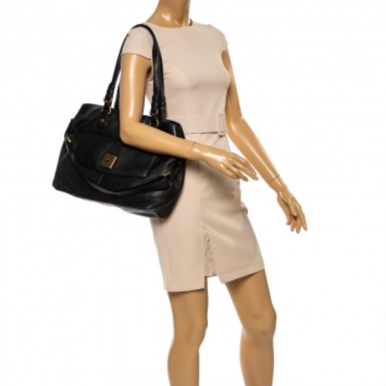 Grab this DKNY tote bag and deliver effortless looks every day. Crafted from quality leather, it comes in a versatile shade of black. It has dual handles, a front pocket with turnlock closure, and a spacious fabric-lined interior. It is finished