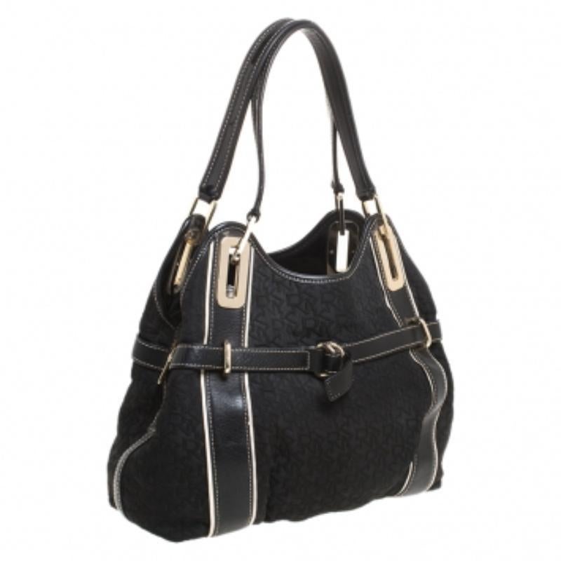 Cet adorable sac fourre-tout DKNY a été confectionné dans le tissu monogramme signature de la marque et présente des bordures en cuir. Ce sac noir est maintenu par deux anses et est doté d'une ceinture à boucle. Son intérieur doublé de satin