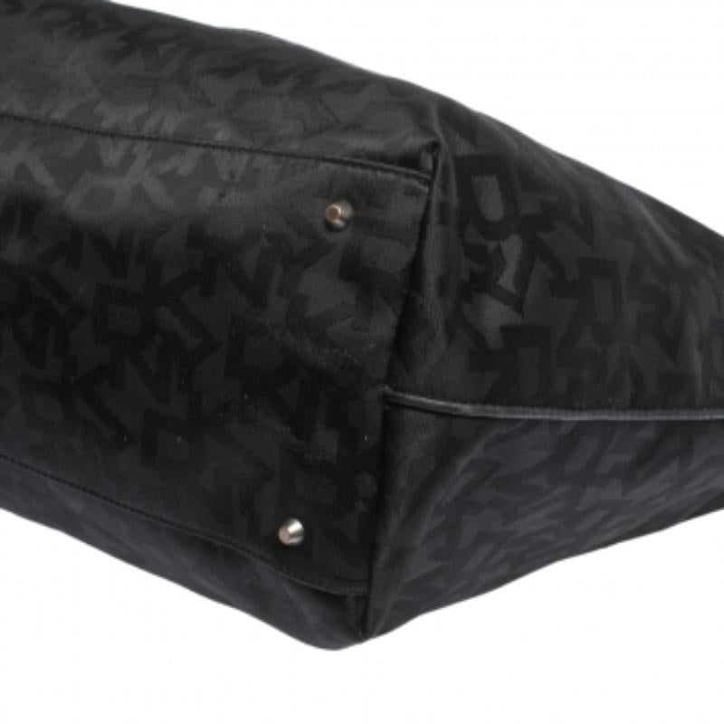 Este impresionante bolso tote de DKNY es una opción excelente para mantener a salvo tus objetos de uso diario. Fabricado en lona de la firma, este bolso en tonos negros se puede peinar fácilmente. El bolso está sujeto por dos asas y forrado de