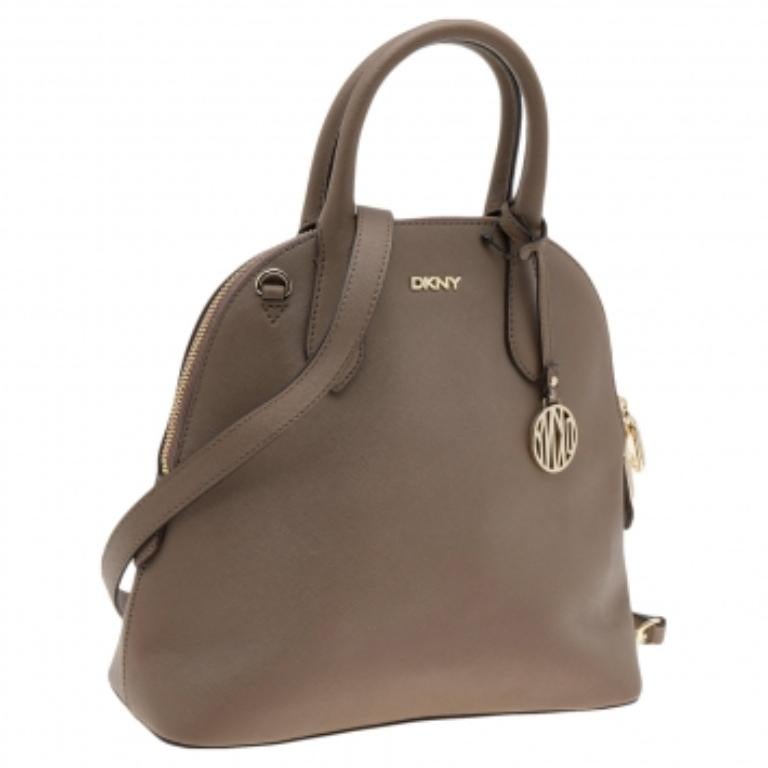 Esta cartera Dkny combina funcionalidad y estilo. Fabricada en piel en el exterior, esta creación presenta un colgante con el logotipo y el nombre de la marca en tono dorado en la parte delantera. Tiene dos asas, una correa larga y un interior