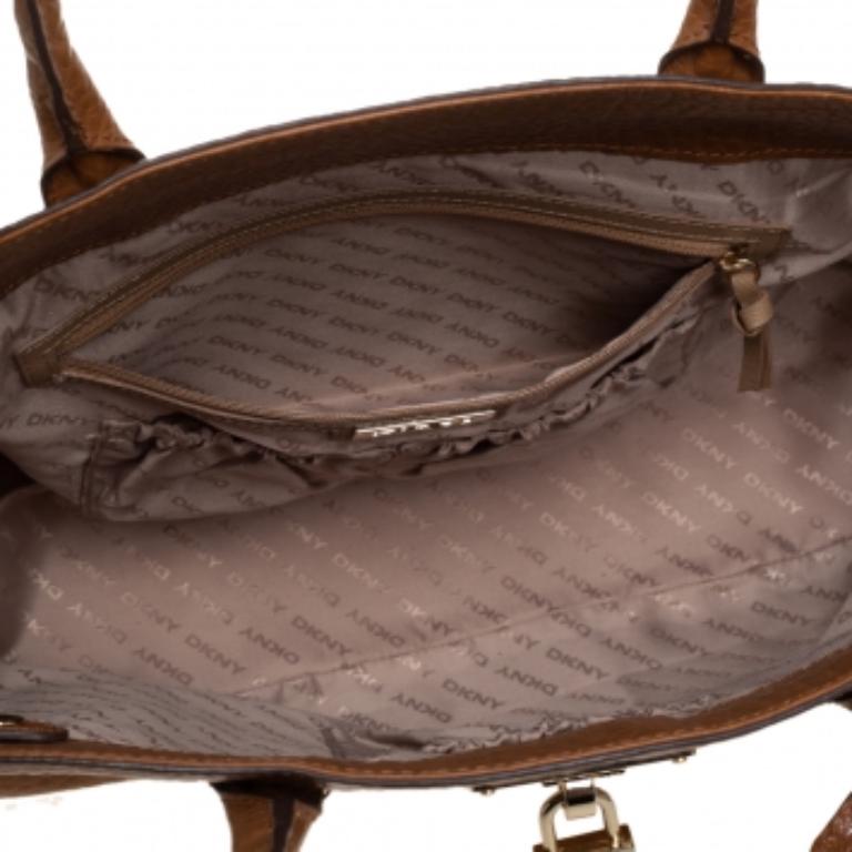 Timelessly elegant and stylish, DKNY's collections capture the effortless, nonchalant finesse of the modern woman. Crafted from leather in a caramel brown hue, this chic tote features a compartmentalized interior with a padlock on the exterior. The