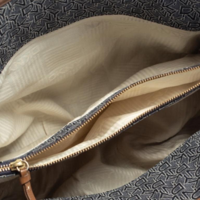 Conçu par des experts, ce superbe sac à main de DKNY vous donnera une allure enviable. Confectionné en toile et en cuir enduits de la signature, il présente un extérieur bien conçu, rehaussé d'accents de quincaillerie en tons dorés. Il s'ouvre sur