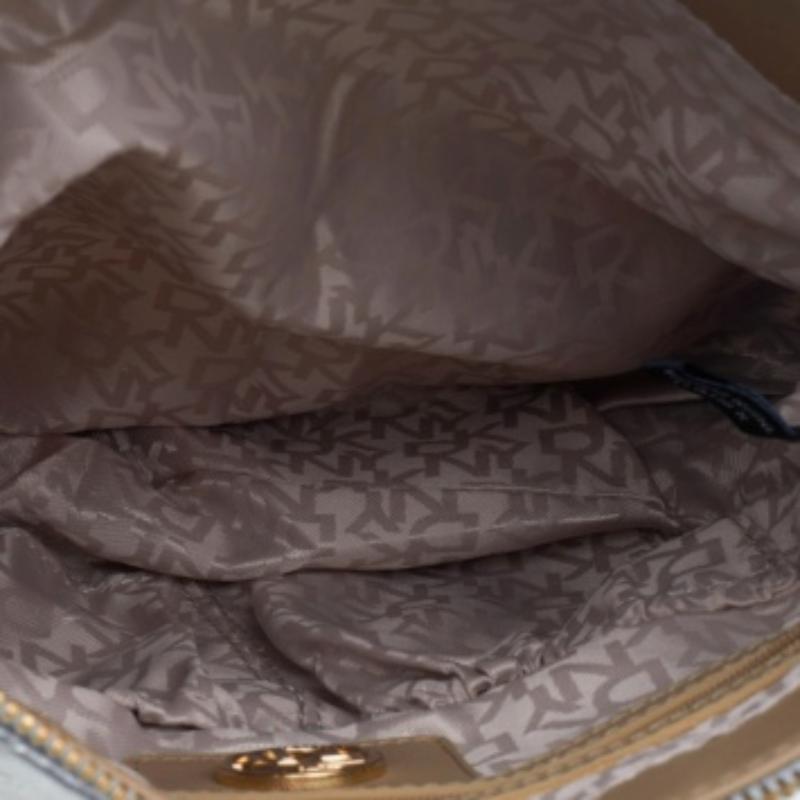 Este bolso bandolera de DKNY añadirá brillo y glamour a tu armario. Está bellamente confeccionada con piel acolchada plateada en el exterior y luce un colgante con el logotipo en tono dorado en la parte delantera. Se sujeta mediante dos correas