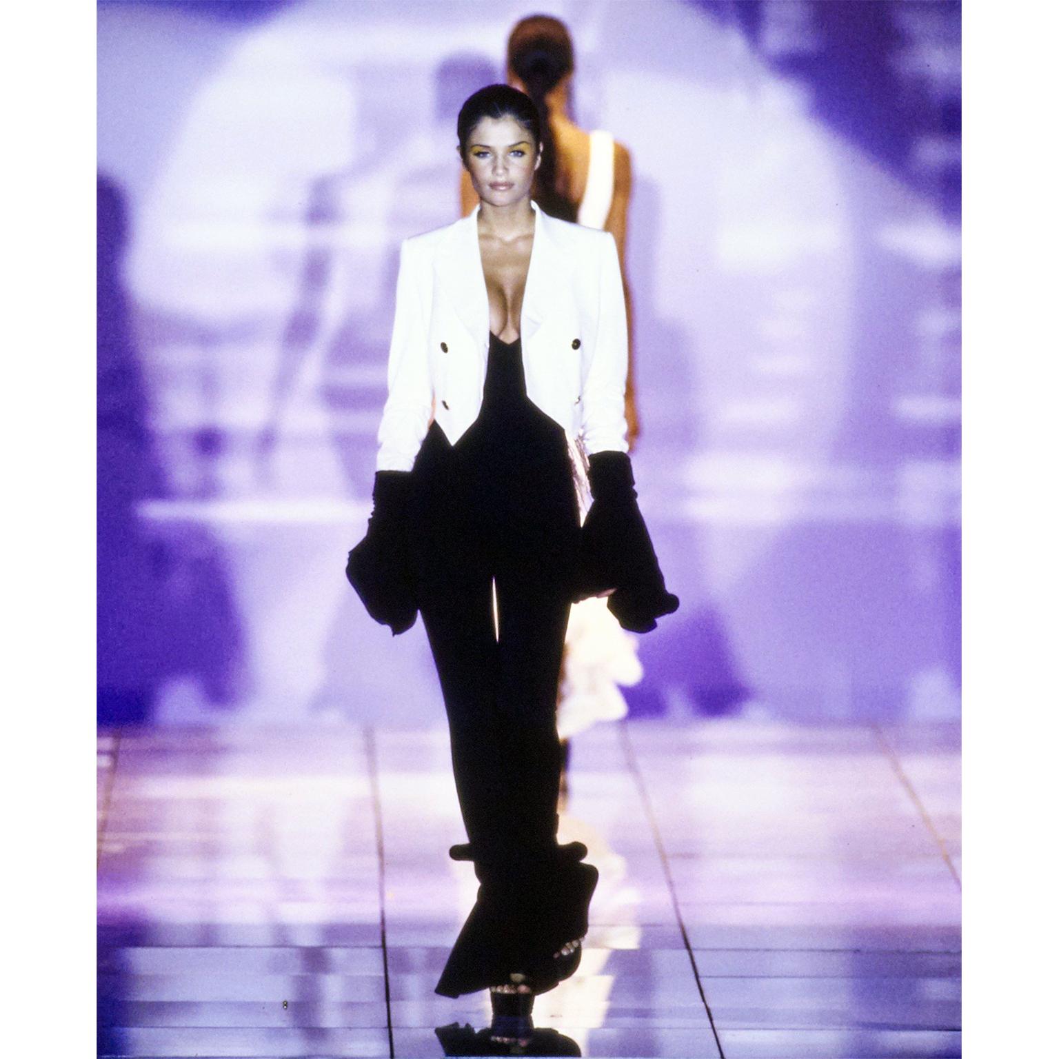 Dies ist ein kultiger schwarzer Stretch-Jumpsuit von Versace mit gerüschtem Saum, den Gianni Versace für seine Frühjahr/Sommer-Kollektion 1993 entworfen hat. Dieser aufsehenerregende Overall besteht aus 90% Viskose, 8% Nylon und 2% Elasthan. Es gibt