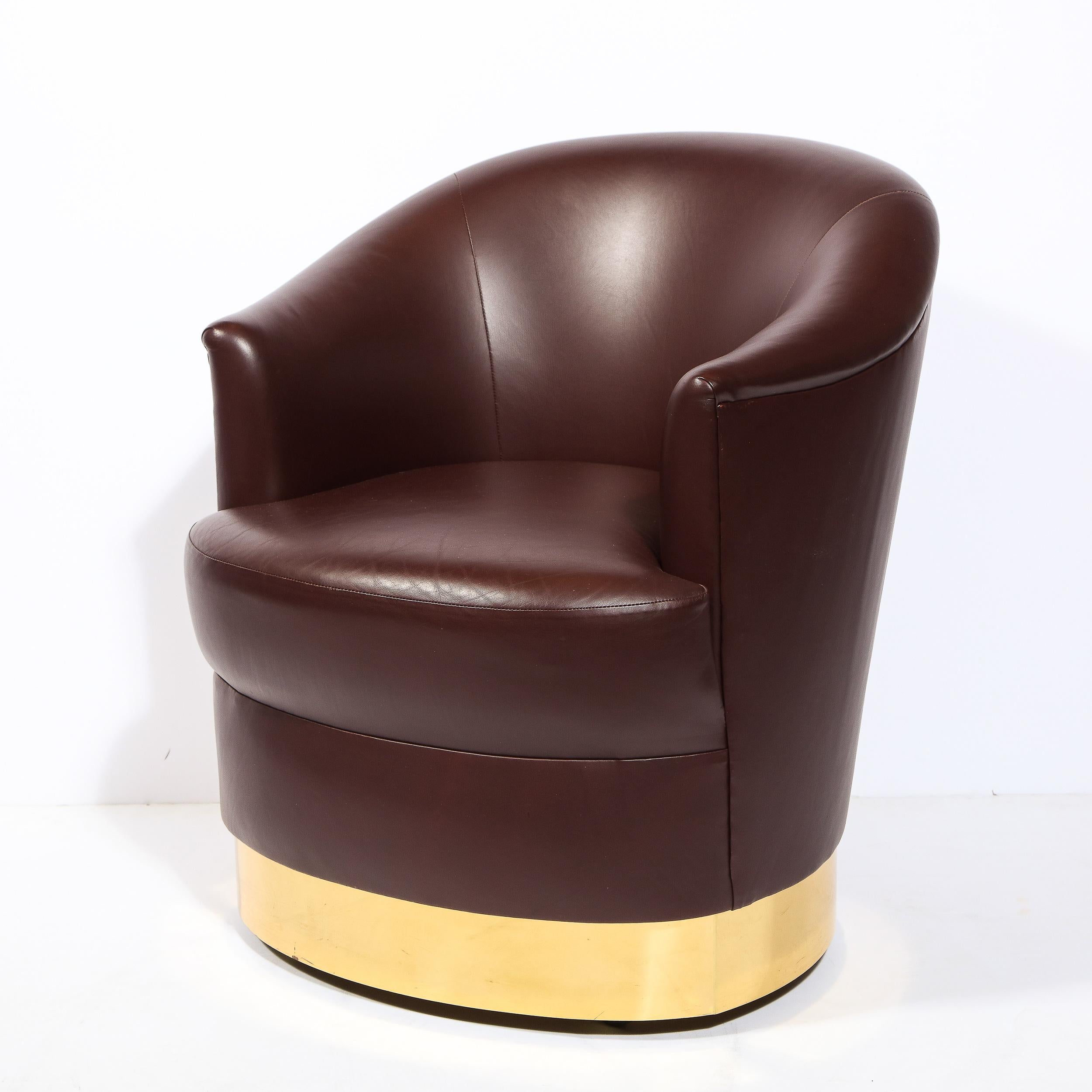 This elegant Mid-Century Modern documented Karl Springer swivel club chair was realized in the United States circa 1985. It offers a sculptural body- full of interesting curvilinear angles- in the original bordeaux Edelman leather sitting on a