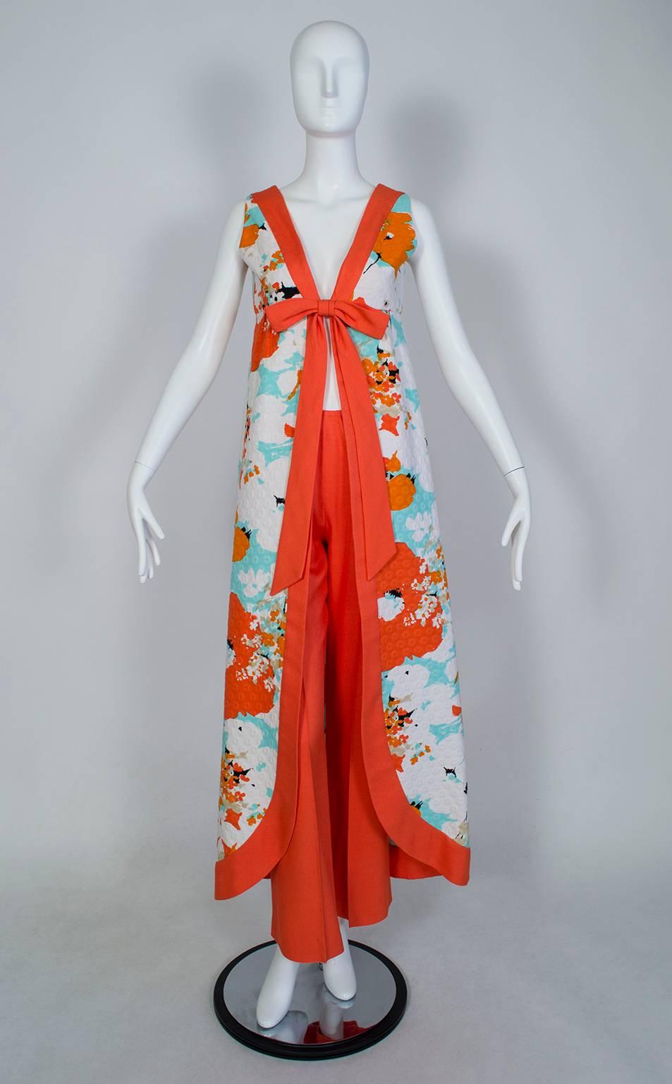 Singular and stunning, this unforgettable 2-piece ensemble is the embodiment of the jet set zeitgeist prevalent in the 1960s and early 70s. Consisting of a split-back maxi dress and coordinating cigarette pants, the outfit can be worn open either in
