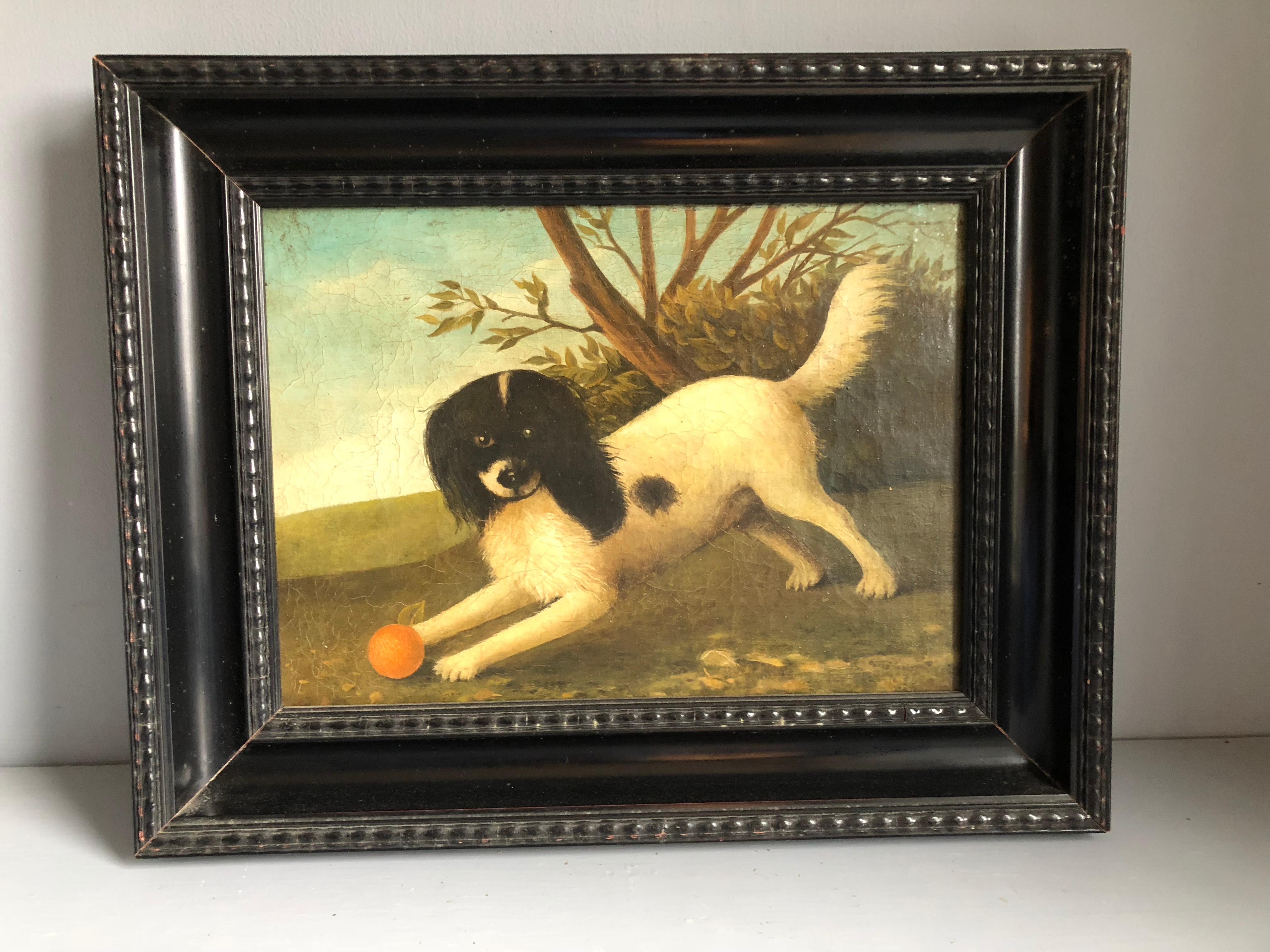 A charming portrait of a dog playing with a ball, 20th century French, in a carved and ebonized wood frame.