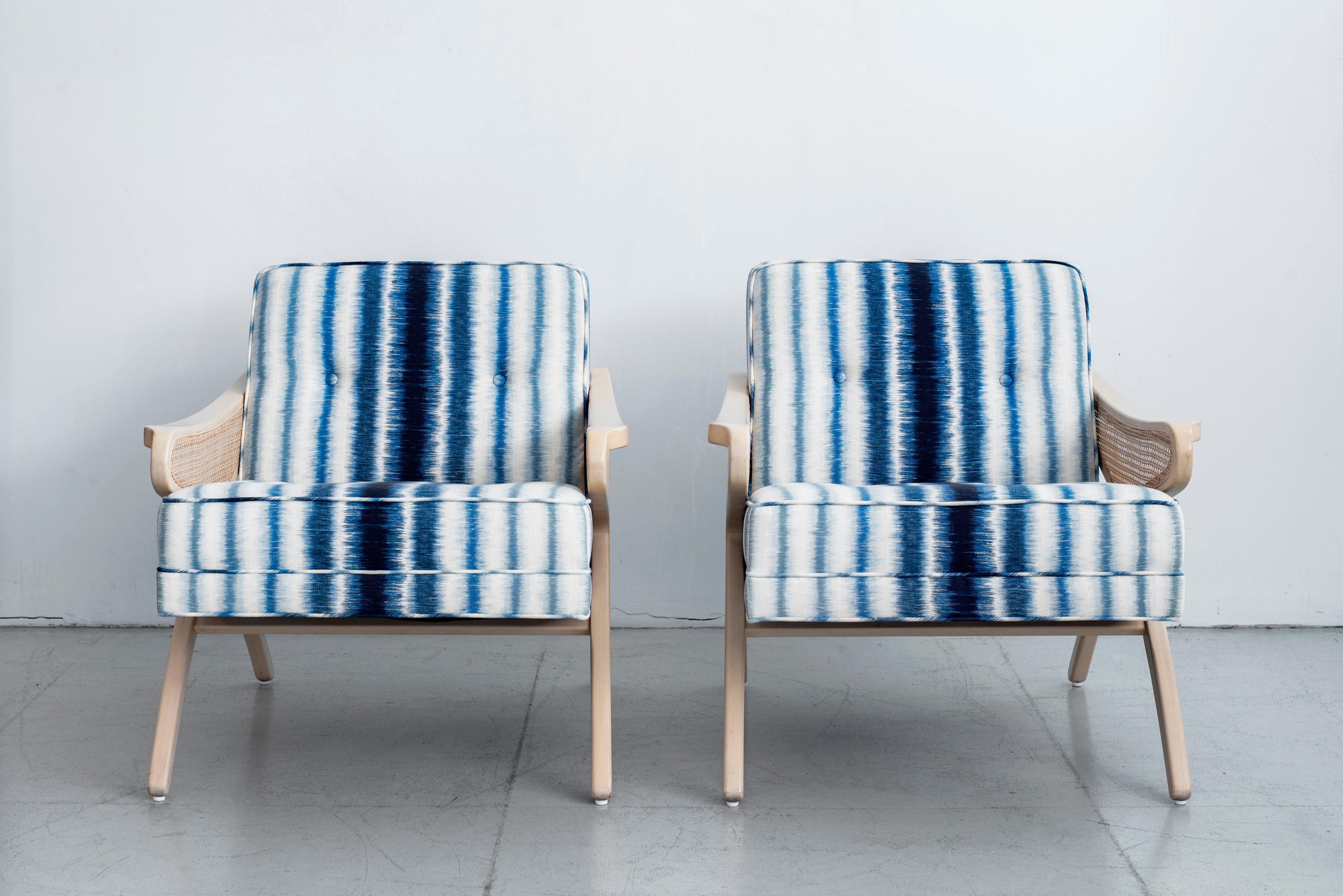 Classic pair of solid maple chairs with light white-washed wood finish. Beautiful caning on both chair arms as well as back of chair compliments the upholstered cushions. Upholstered in bright blue ikat print fabric. Perfect for the home or office.