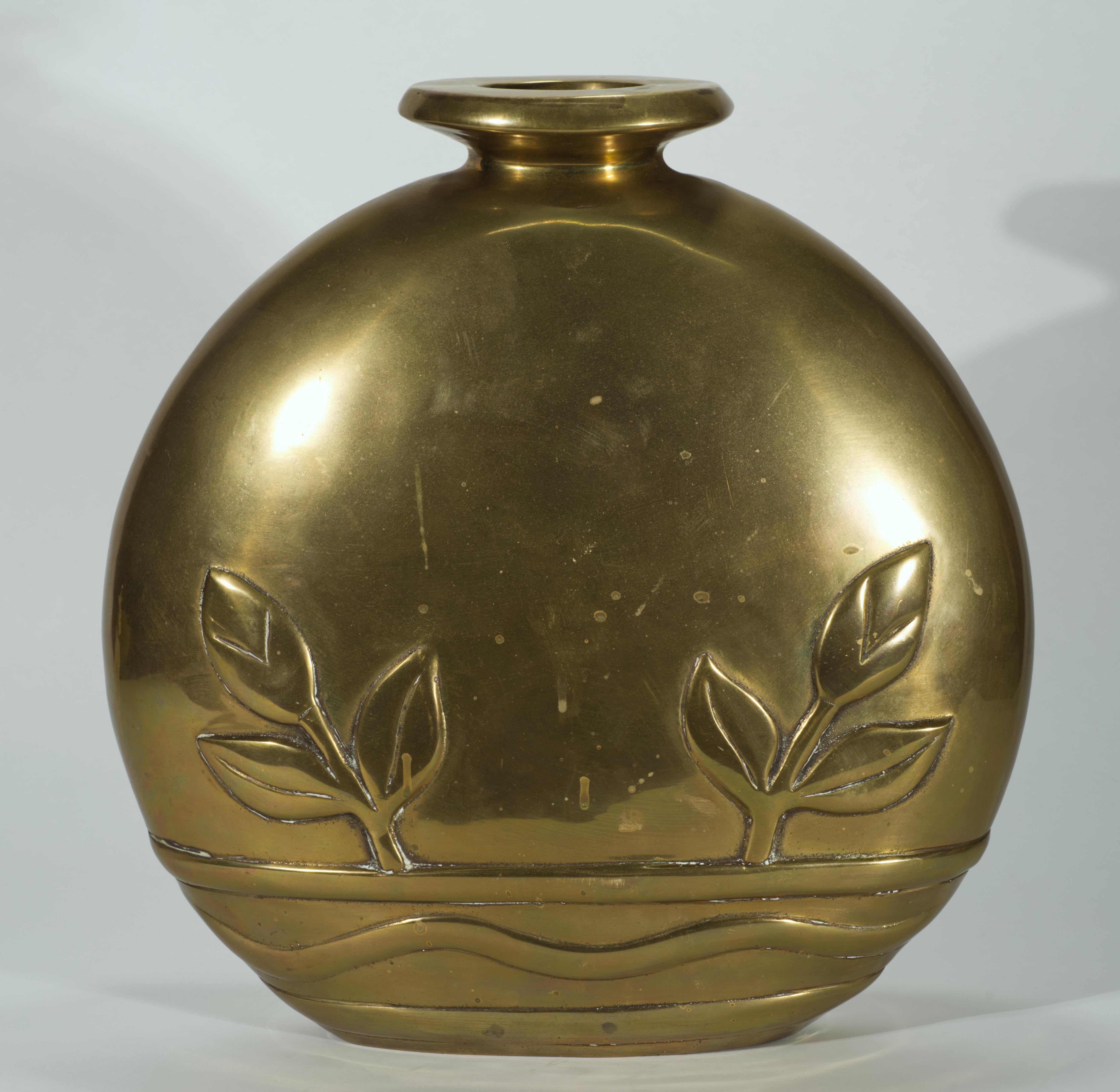 Large, sculptural vintage brass vase features an abstract Art Deco decor of two stems with flower buds and leaves, arising from a wide graphic decorative band. The oversized, heavy vase has round front and back and flattened sides, resulting in
