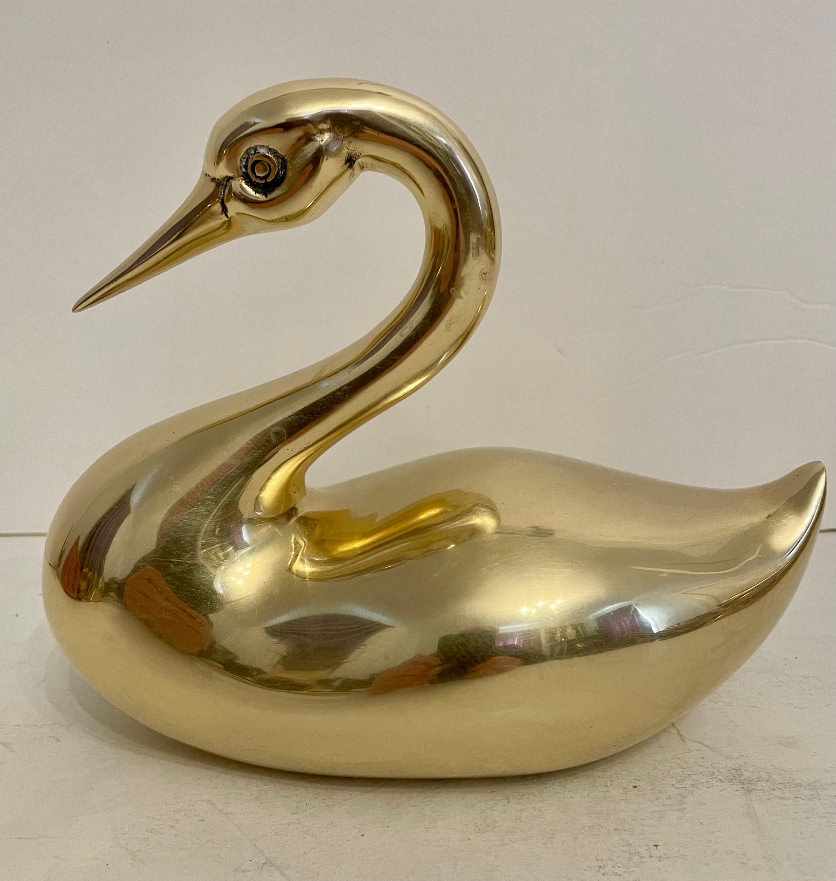 Scultura di cigno in ottone di grandi dimensioni Dolbi Cashier.  Pesante per le dimensioni. Qualità superiore.  Si trova su una libreria o su un tavolo. Buone condizioni di lucidatura a mano, le aree chiare e scure sono dovute ai riflessi della luce.