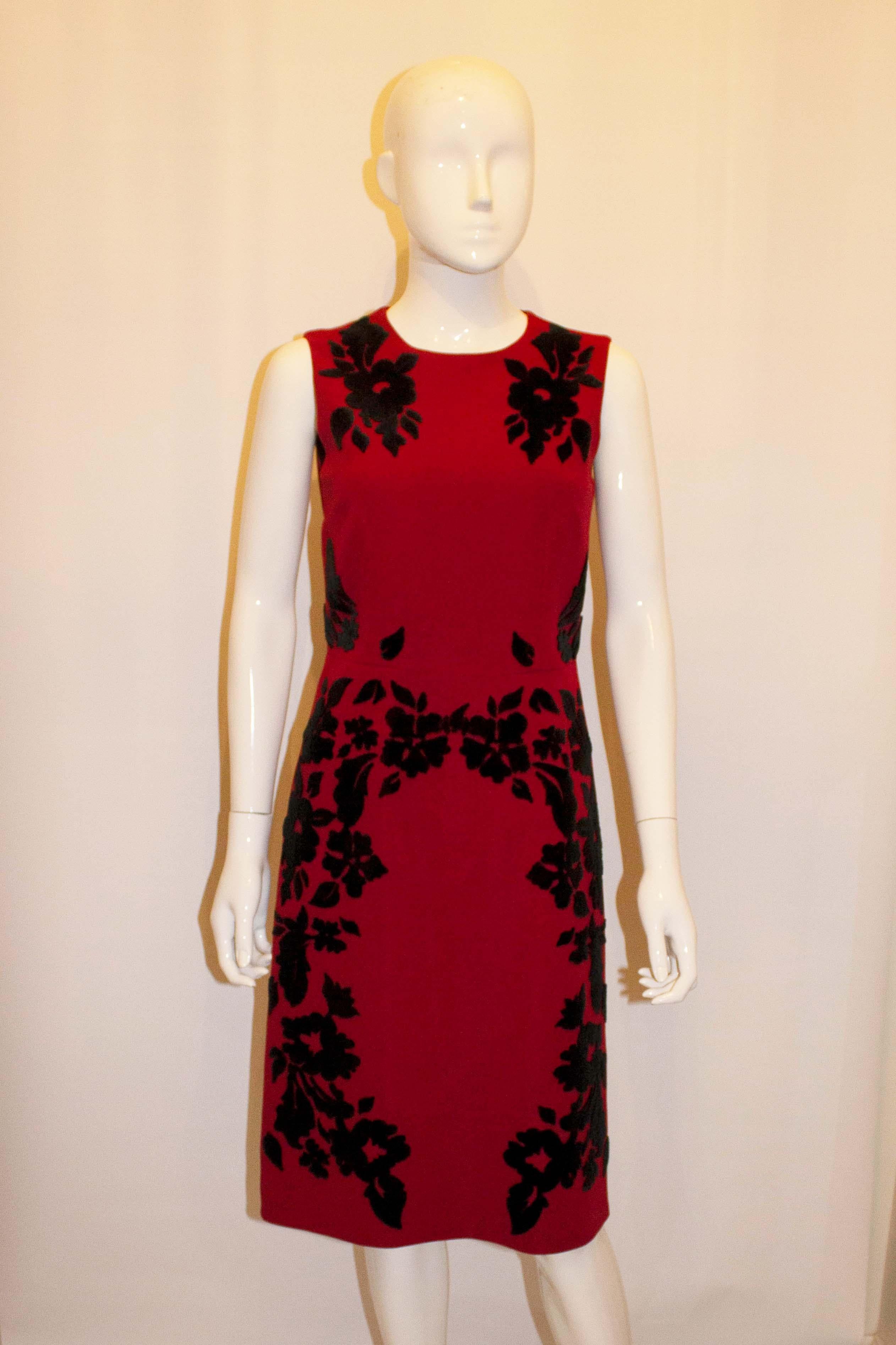 Une robe amusante pour les fêtes de fin d'année, signée Dolce et Gabanna. La robe  est en laine rouge avec des détails en applique noirs. Il présente une magnifique confection, une fermeture éclair centrale au dos et est entièrement doublé. 
Mesures