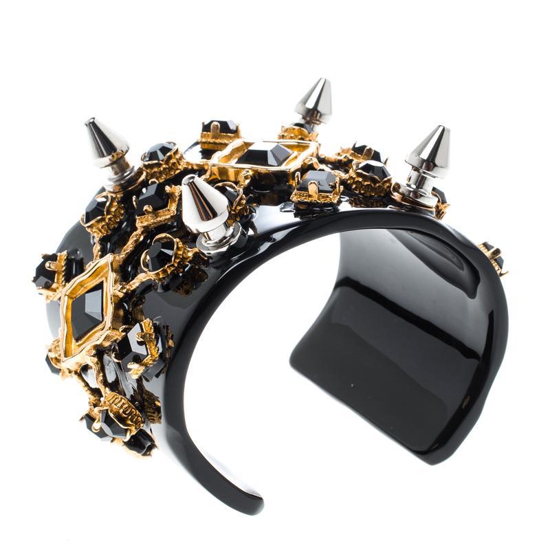 Zeigen Sie Ihre Liebe zu funkelnden und luxuriösen Accessoires mit diesem atemberaubenden Armband von Dolce&Gabbana. Sie hat eine offene Manschette aus Harz, die mit kunstvoll angeordneten Kristallen und Stacheln verziert ist und so einen modernen