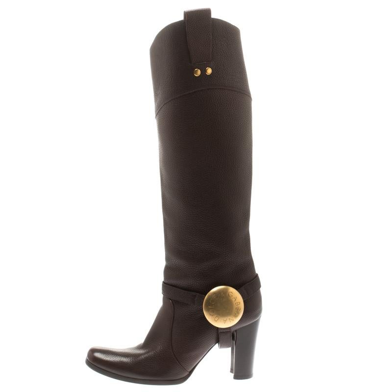 Promising to make you look like a true fashionista, these Dolce And Gabbana boots are a must buy! The brown knee-length boots are crafted from leather and styled with square toes. They feature an engraved gold-tone buckle strao detailing and come