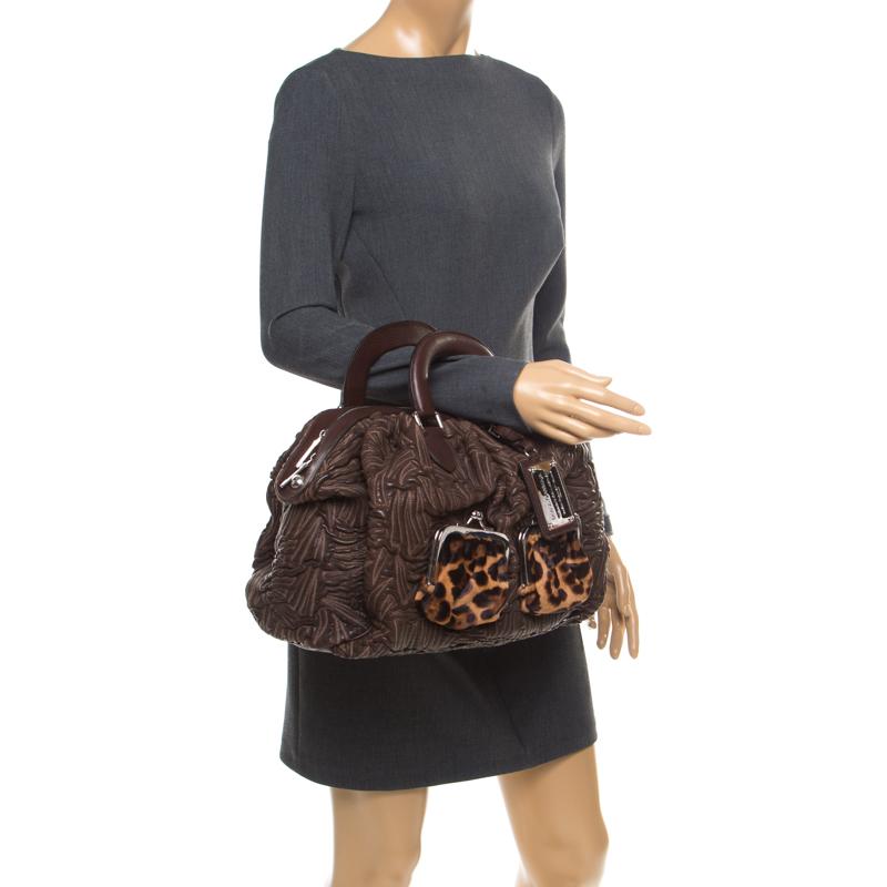 This Miss Curly bag by Dolce & Gabbana is a piece all fashionistas must look out for! Meticulously crafted from textured leather, it features a brown shade and leopard-printed kiss lock pockets. The bag is equipped with a spacious fabric interior