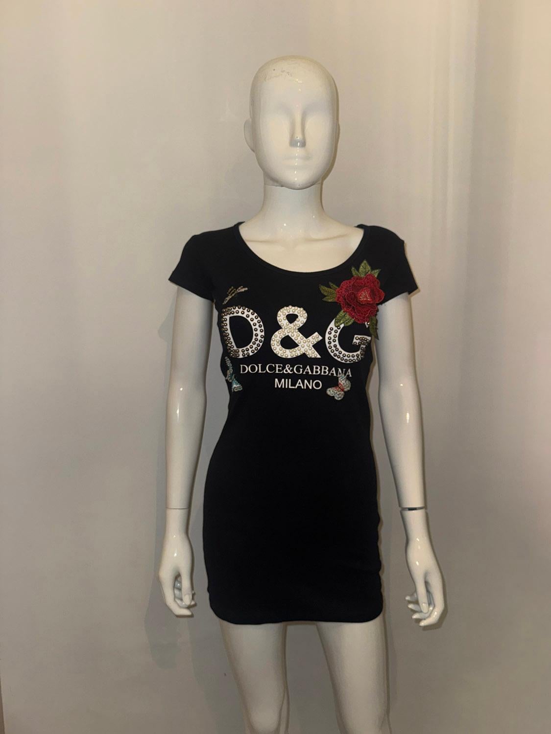 Una splendida t-shirt di Dolce e Gabanna. In cotone nero, la t-shirt è dotata di  maniche a mantellina e scollatura rotonda. Ha  un'ape, una farfalla e un abbellimento floreale  più ' D & G ' nel dettaglio delle perline.
Taglia S Misure. Seno fino a