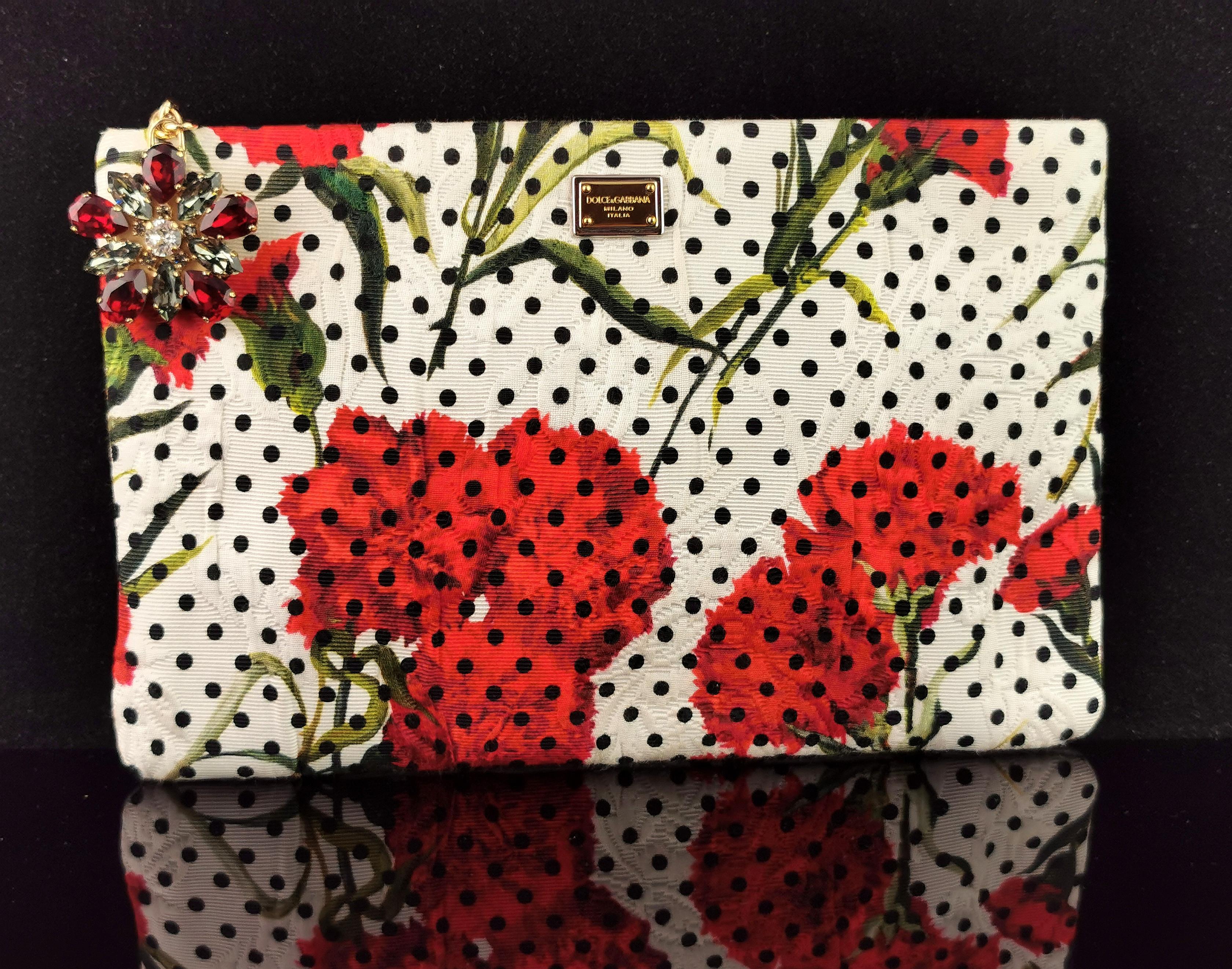 A gorgeous Dolce and Gabbana floral clutch purse.

It is made from a soft printed canvas with a red carnation flower and Polka dot print.

Lined in cream satin with a gold tone metal brand tag and small pocket.

Gold tone metal brand tag to the