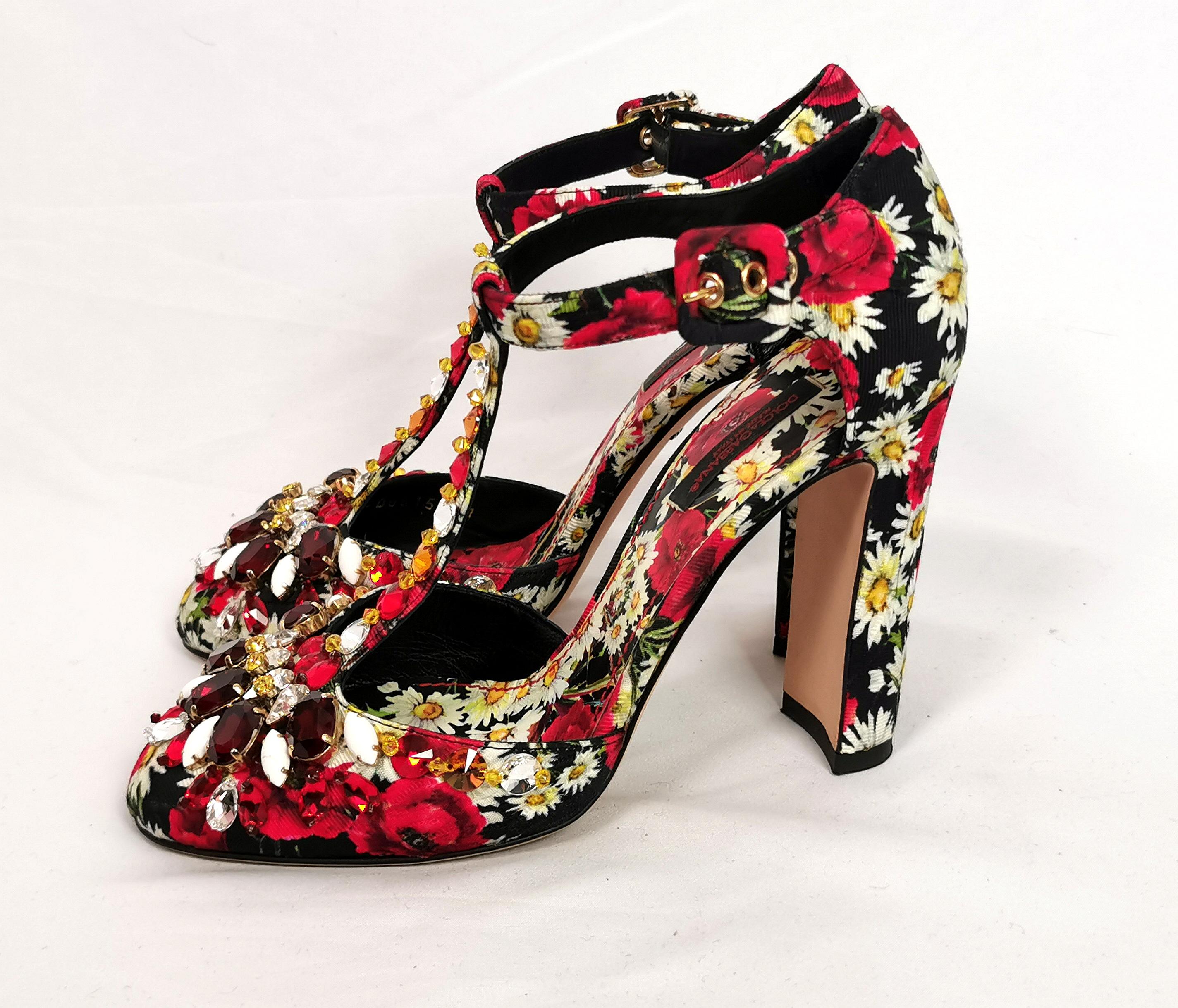 A truly gorgeous pair of Dolce and Gabbana floral jewelled heeled sandals.

They have a T bar shape with chunky high heels in the most fantastic all over printed canvas with a floral design of poppies and daisies on a black ground.

They fasten with