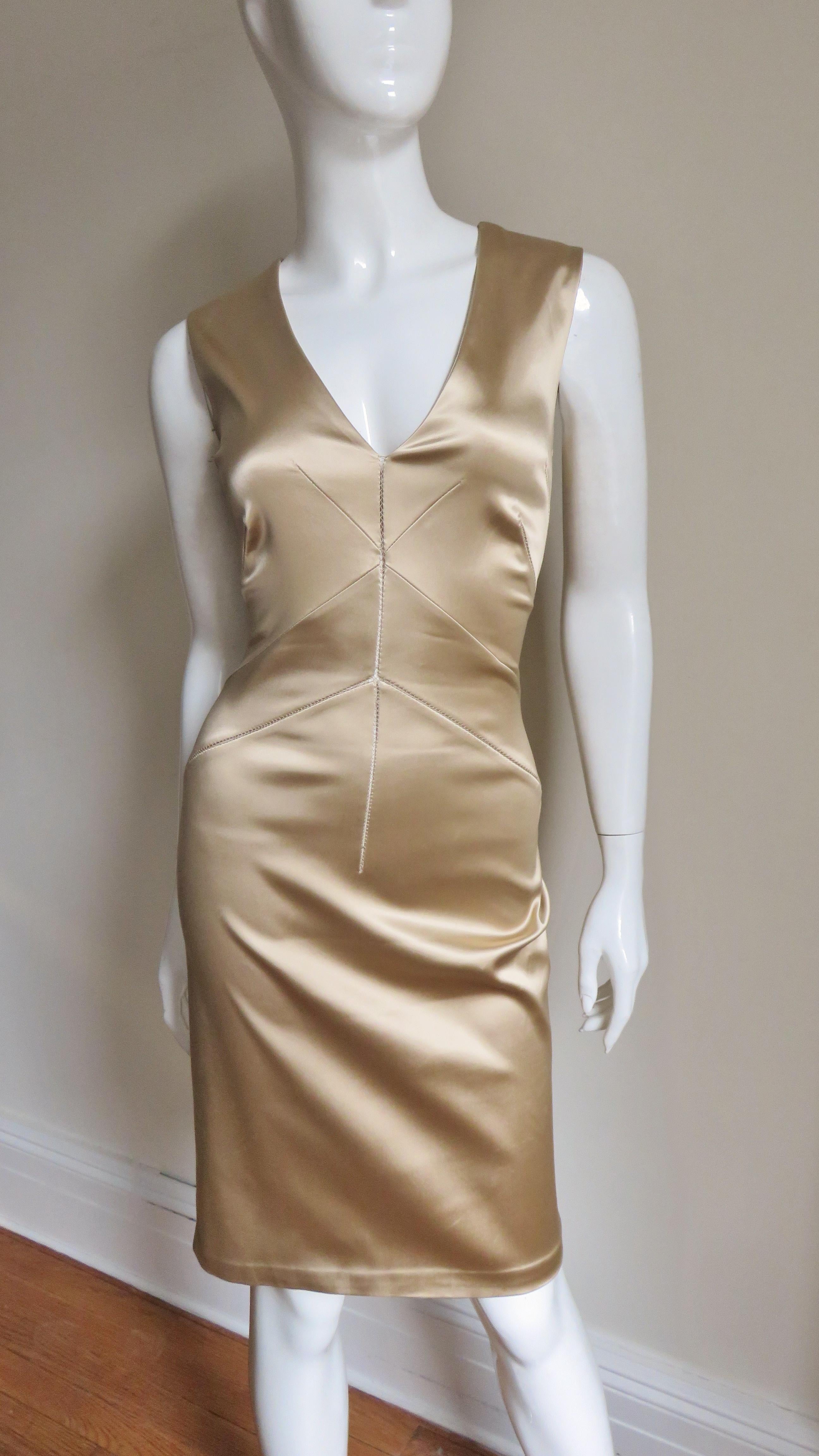 A fabulous gold stretch satin dress from Dolce and Gabbana.  It is sleeveless with a V neckline front and back and a body conscious fit created through the fabric and angular seaming.  It closes up the back with hooks and eyes hidden under a