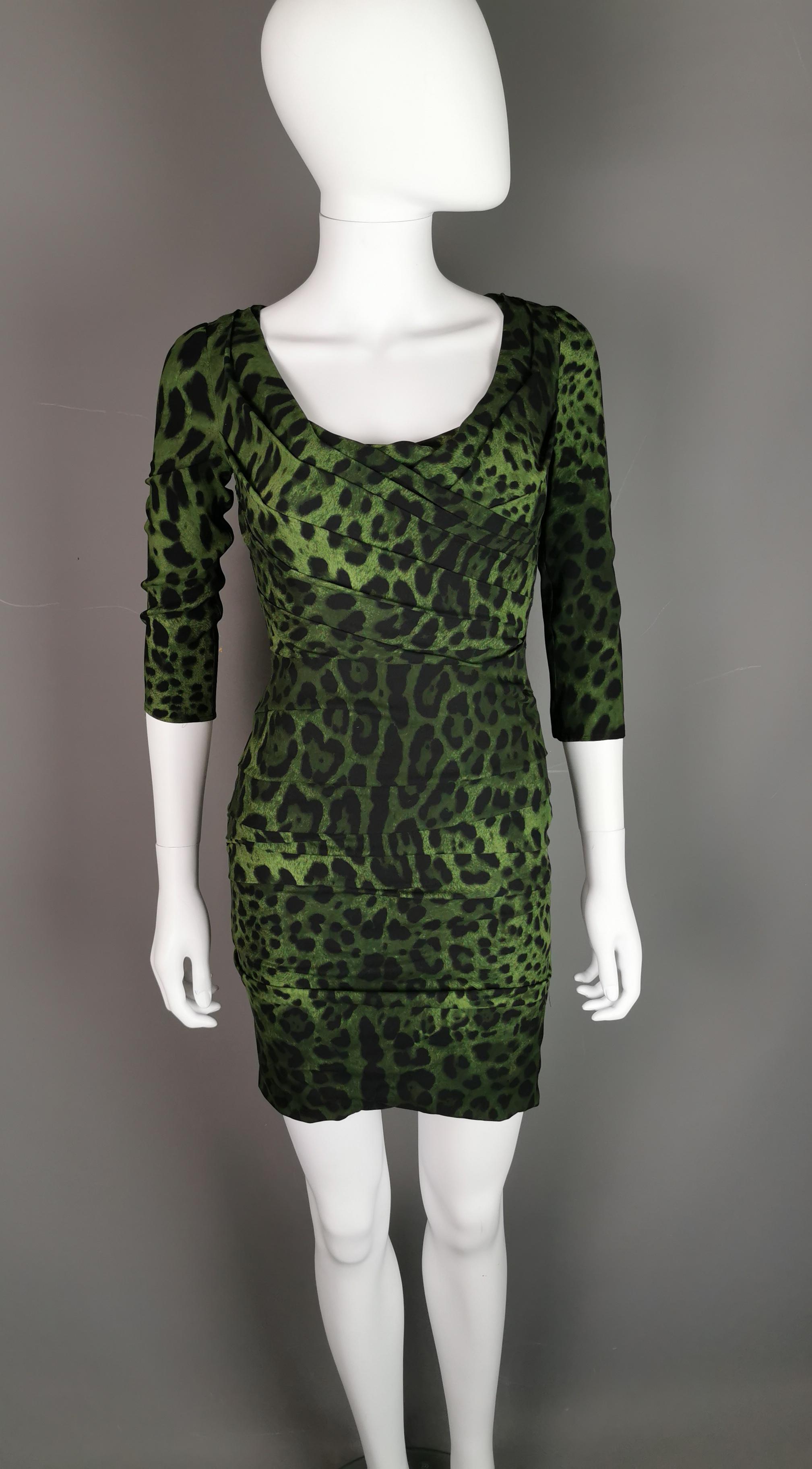 A gorgeous Dolce and Gabbana green and black leopard print bodycon mini dress.

The dress has low sloping shoulders and ruched detailing, the neckline is fairly low and rounded accentuated by the ruched design.

It has a slim figure hugging fit and