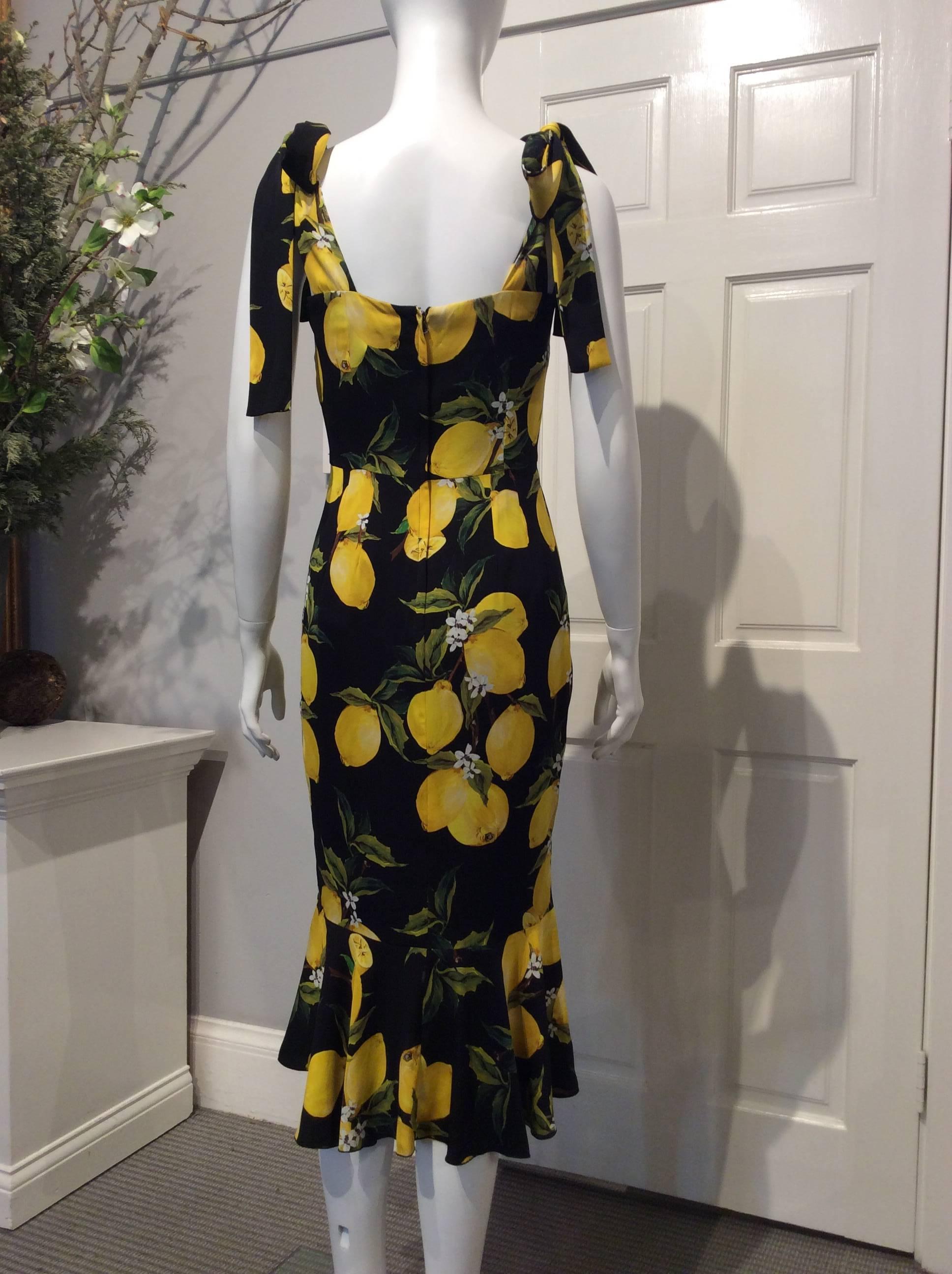 Dolce and Gabbana black and yellow lemon print fitted dress with a flounce hem. It has a square neckline and self-tie 2’ wide shoulder straps. It closes with a hidden zipper in the back. The fabric content of the dress and of the black lining is 94%