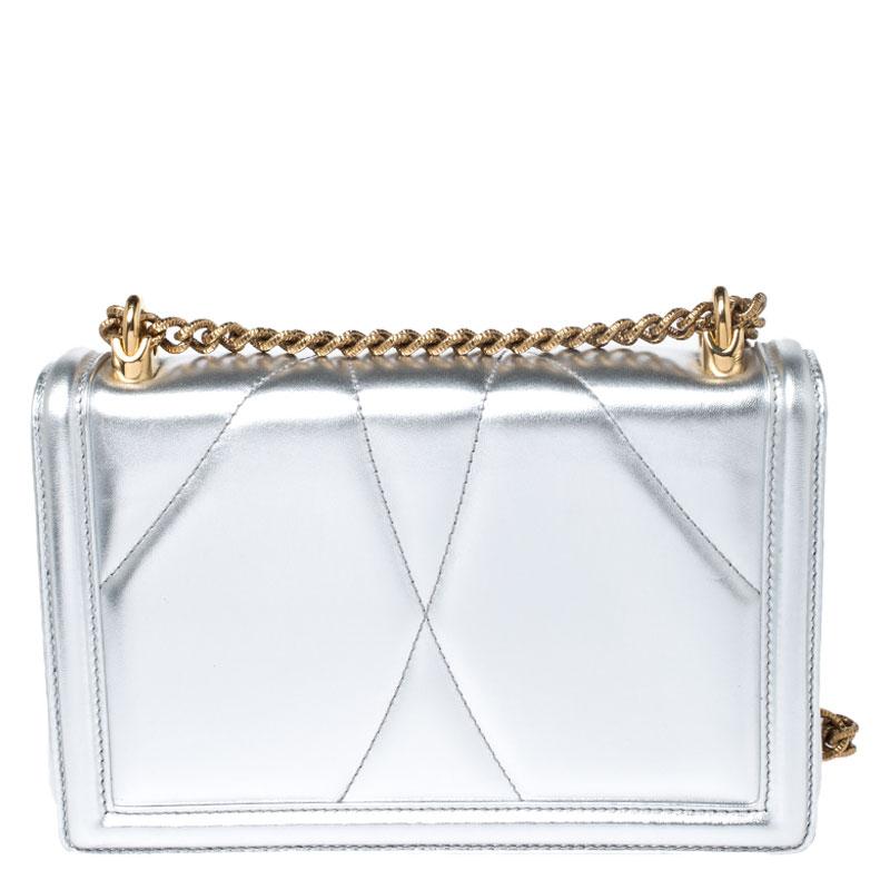 Step out in style by adorning this bag from Dolce&Gabbana. It has been crafted from silver leather and flaunts the Devotion heart motif in gold-tone on the front. It features a well-designed leather-lined interior housing a pocket. The bag is