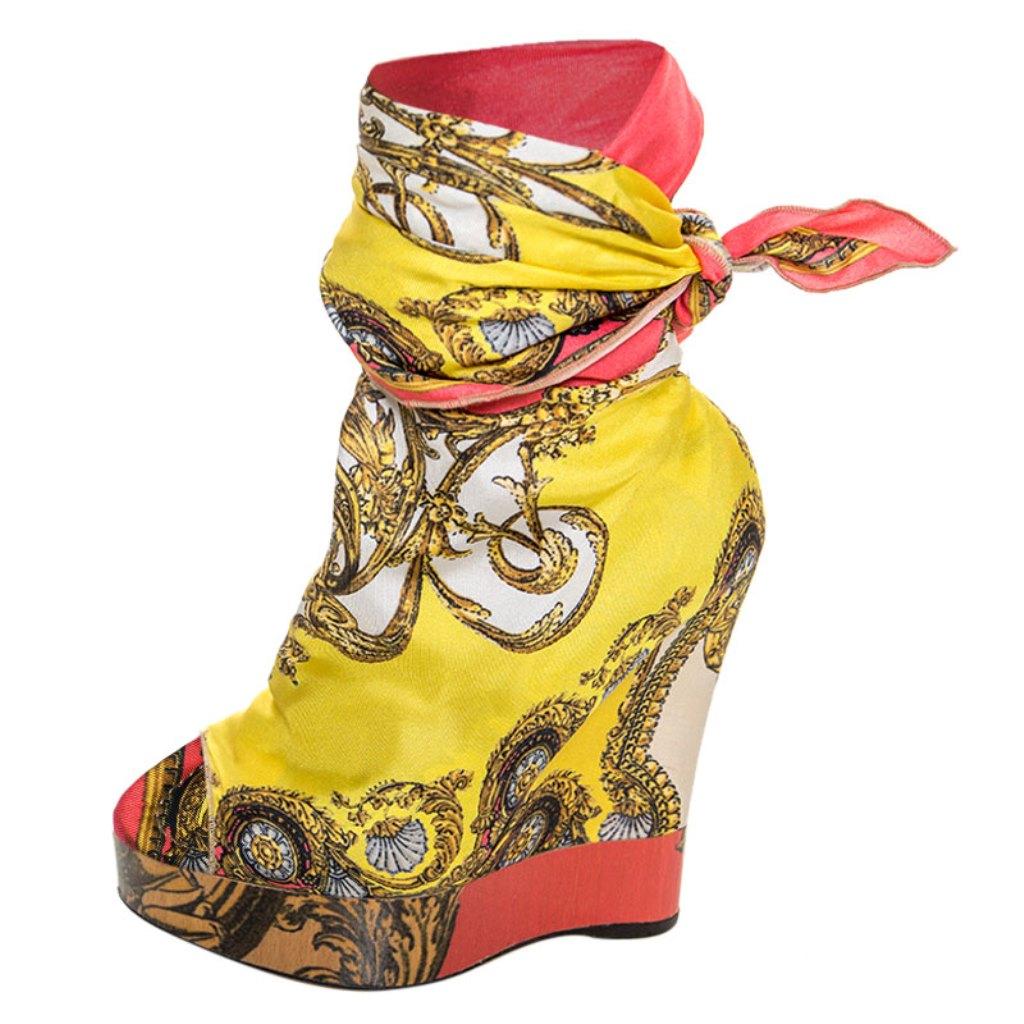 These gorgeous pumps by Dolce & Gabbana have been crafted exquisitely. Made from printed fabric, they feature an open toe silhouette with a scarf wrap detailing, 13.5 cm wedge heels and leather lining, insoles and soles. This multicolored pair is
