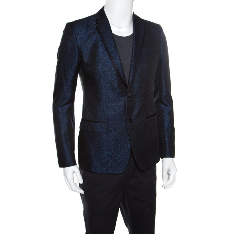 For a look that leaves people stunned, choose this amazing blazer from the house of Dolce and Gabbana. It features a metallic finish with a navy blue hue. Crafted fabulously into a fine structure with satin trims, this one is equipped with a
