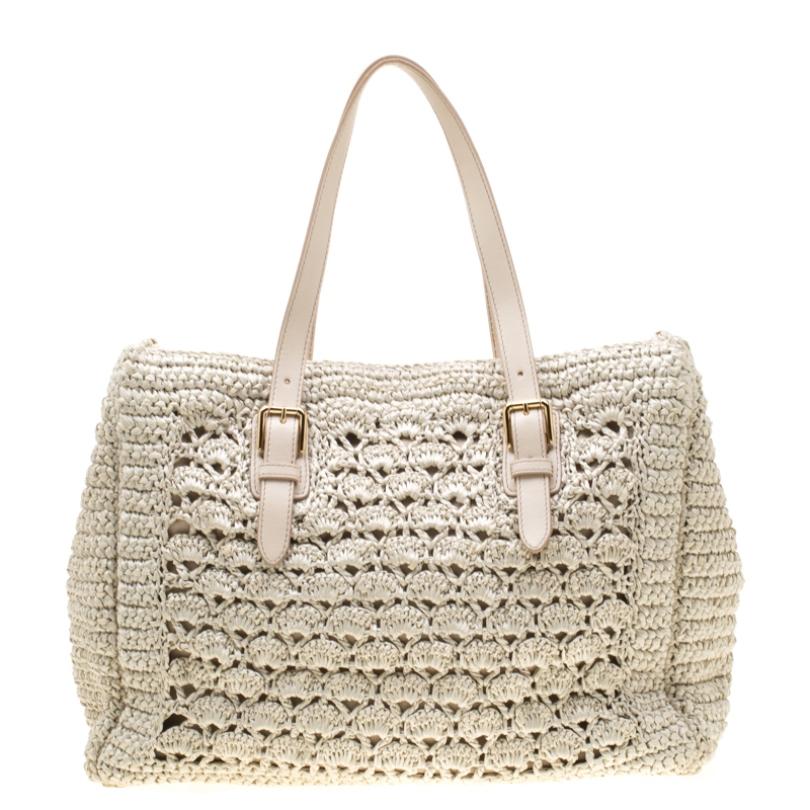 This Alma tote from the house of Dolce & Gabbana is designed in off-white Raffia crochet and comes with metal studs on the leather base. It features two top handles, a fabric-lined interior and the metal logo plaque on the front. This well-sized