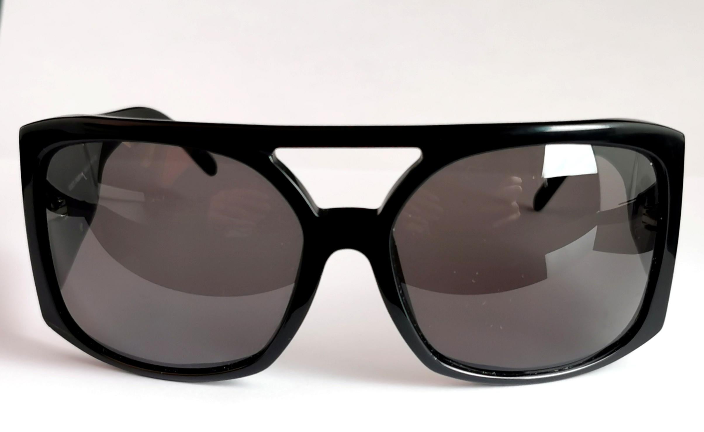 A gorgeous pair of Dolce and Gabbana sunglasses.

Black lenses and glossy black acetate frames in an oversized style and with a very slight wraparound.

The sunglasses have a large D on one side and a large G on the other in silver tone metal and