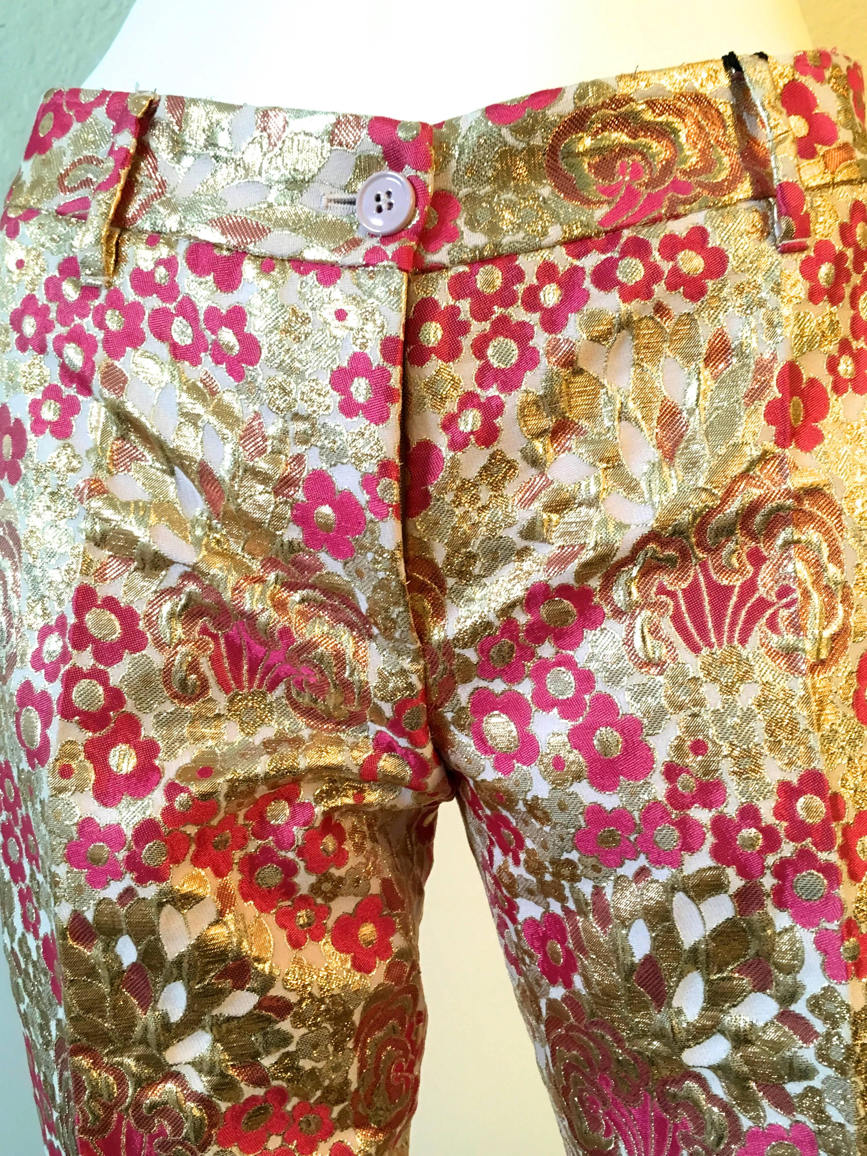 Presented here is a fabulous pair of Dolce and Gabbana pants. The stunning pair of pants is a size 38. The silk brocade fabric is absolutely magnificent and the fabric is woven threads of gold and light pink and magenta flowers throughout. A