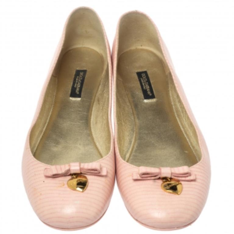 Ces ballerines roses de Dolce and Gabbana confèrent un attrait luxueux à vos tenues décontractées. Confectionnées en cuir gaufré au lézard et ornées de nœuds et de cœurs gravés en ton or sur l'empeigne, elles constituent le choix idéal lorsque vous