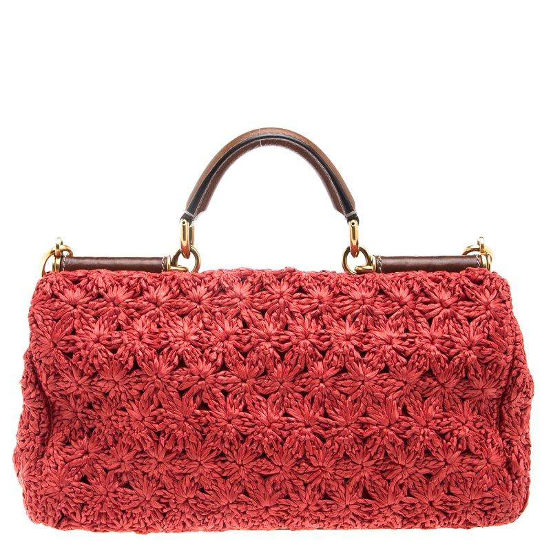 This beautiful red colored Miss Sicily bag from Dolce and Gabbana has a structured design. The bag features a woven raffia design all over. It has a top handle and an adjustable detachable shoulder strap. The front flap opens to a Leopard print
