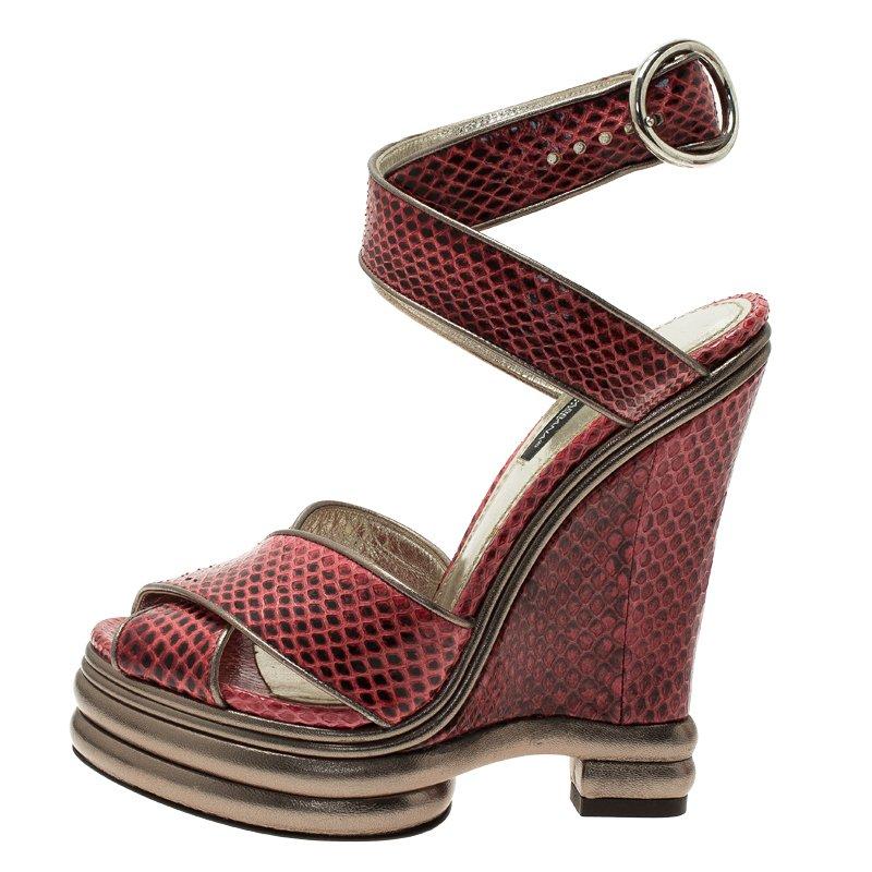 These sandals from Dolce and Gabbana are adored for their stylish silhouette. Crafted from red python leather, these sandals are elevated on 13.5 cm wedge heels. They are accented with crisscross vamp straps and ankle straps with silver-tone round