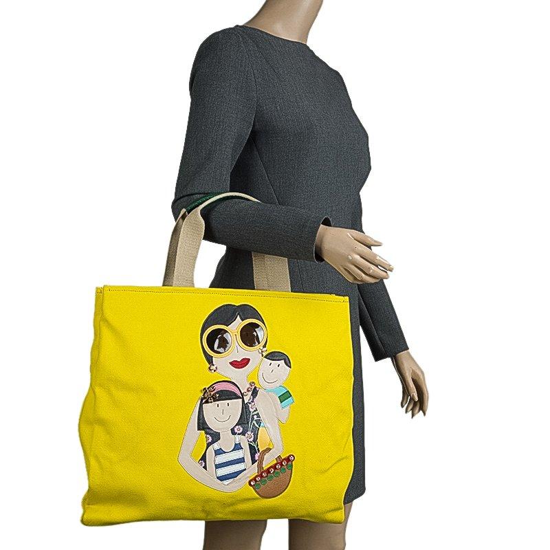 This adorable Maria shopper tote from Dolce and Gabbana is made from yellow canvas. The bright bag has a cute family patch on the front and dual top handles. The buttoned closure opens to a satin lined polka dot print interior. Shop in style with