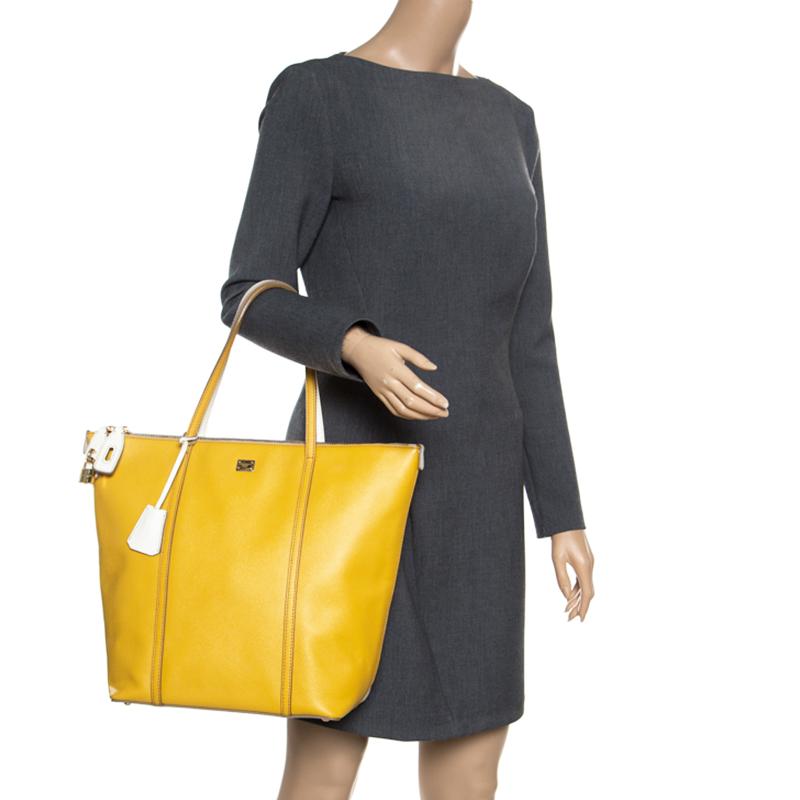 How fabulously designed is this Miss Escape tote from Dolce and Gabbana! Vibrant yellow on one side and pristine off-white on the other, this tote is crafted from leather and features a chic silhouette. It flaunts a double zip top closure, dual top