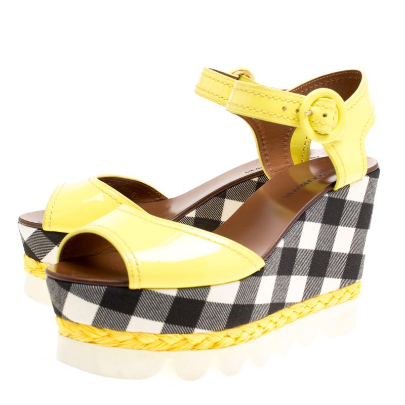 Constructed in yellow patent leather, these Dolce and Gabbana wedge sandals give subtle hints of fun style to your look. Featuring monochrome checked pattern on the platforms and wedges, these shoes are complete with matching yellow espadrille