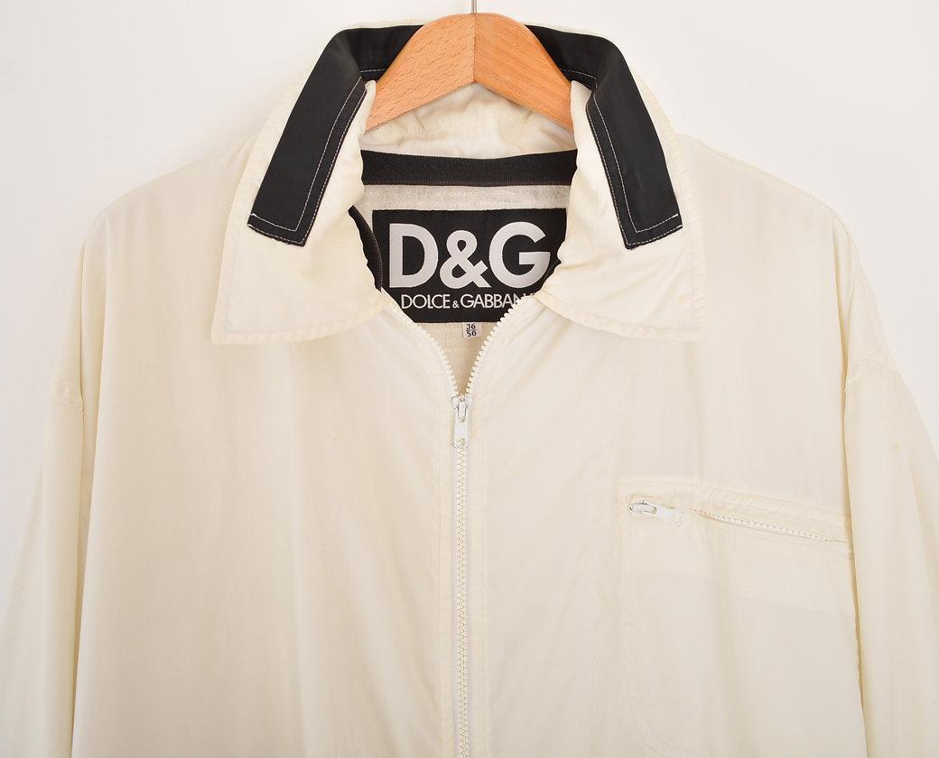 1990's DOLCE & GABBANA off-white nylon jacket, featuring removeable 'D&G' taped velcro patch to the front and taped 'D&G' spellout to the reverse. 
 
Features;
Removeable D&G Velcro patch
x3 Front pockets
Concealed packaway hood
Adjustable